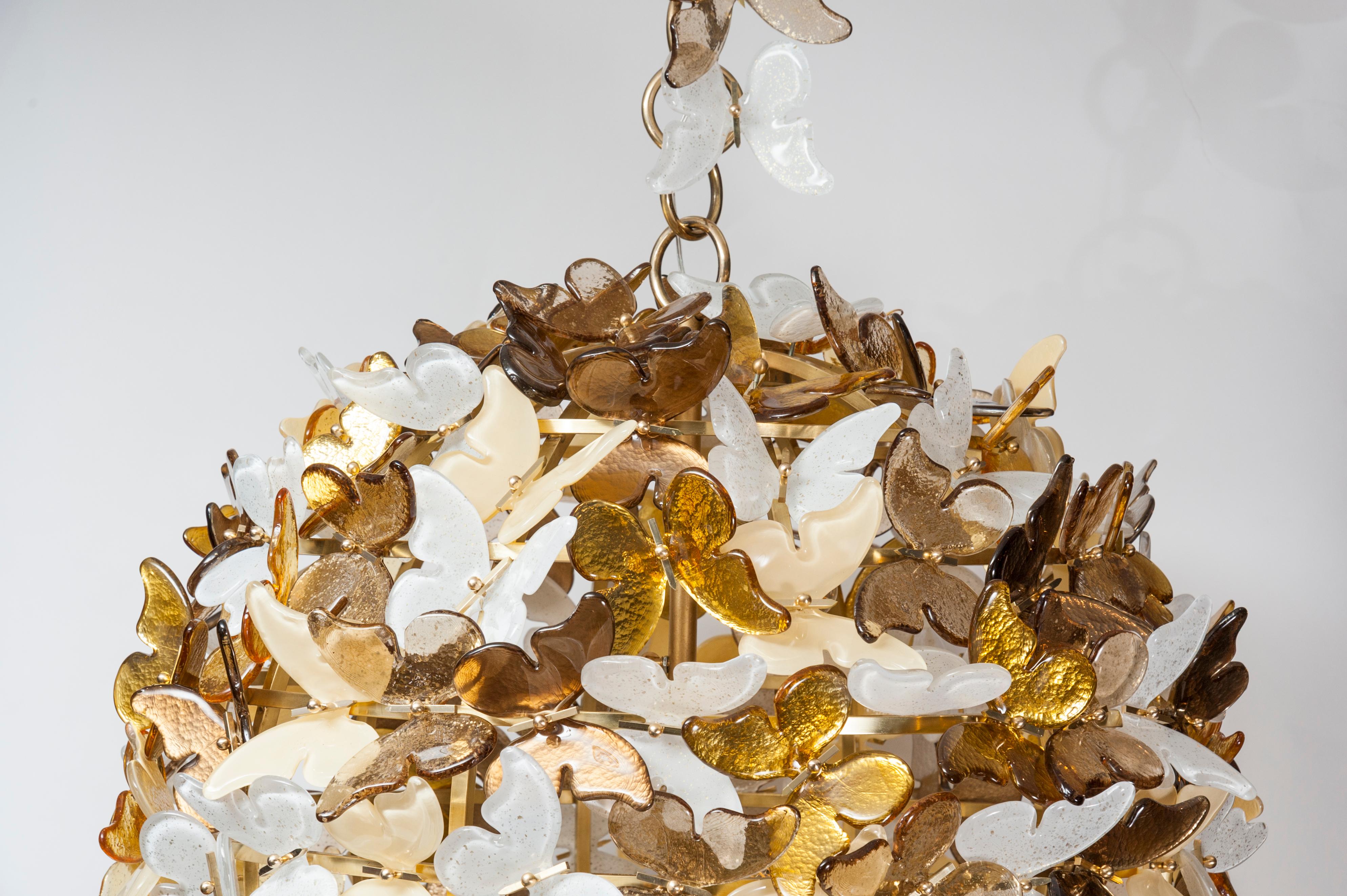 This majestic chandelier is featuring a brass armature and Murano glass butterflies in colored in gold, yellow and amber. Modern creation by studio Glustin. 
The size is customizable.