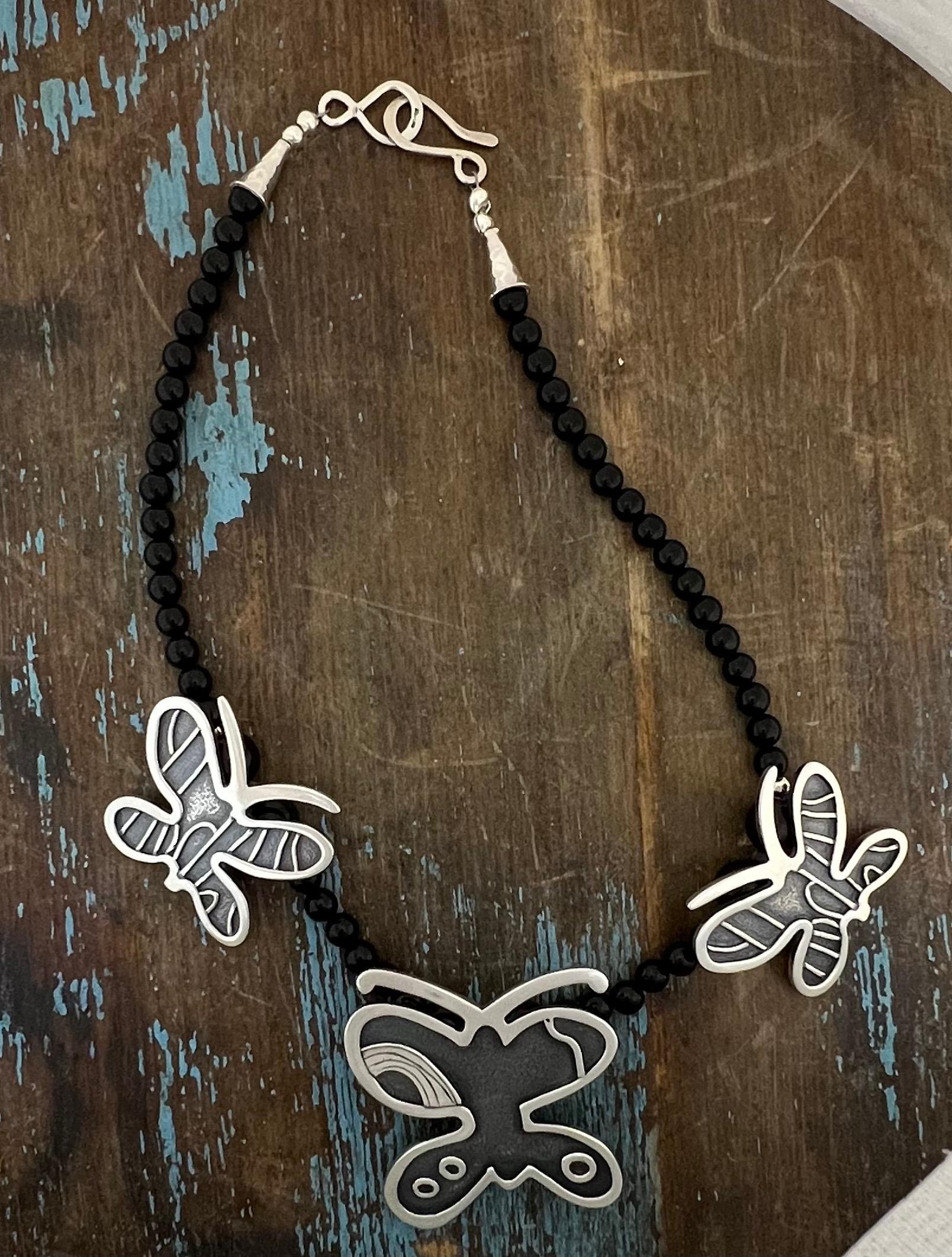 Butterflies necklace designed by Melanie A. Yazzie, Navajo, silver, onxy beads

Melanie A. Yazzie (Navajo-Diné) is a highly regarded multimedia artist known for her printmaking, paintings, sculpture, and jewelry designs. She has exhibited, lectured,