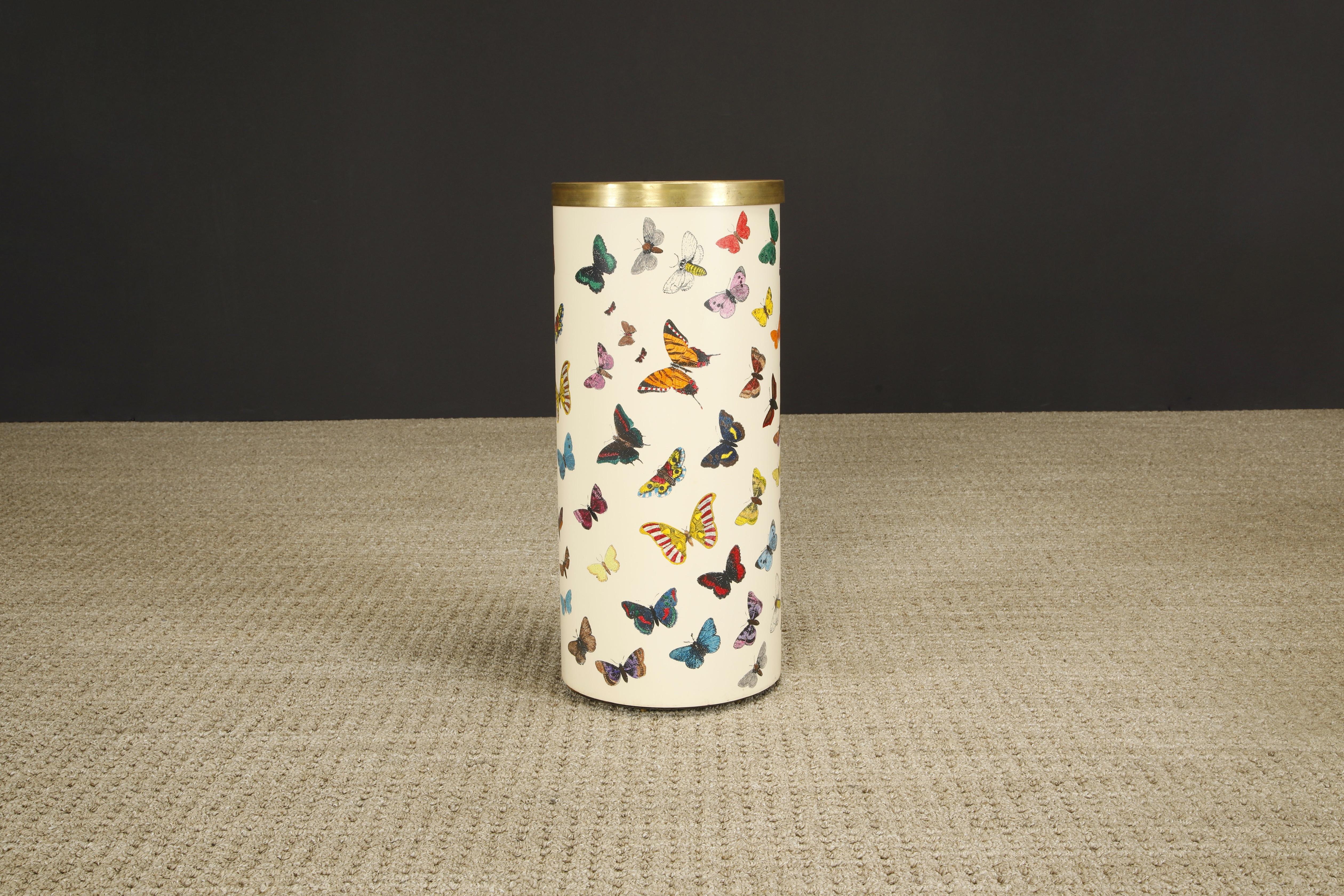 This rare and coveted collectors item is the 'Farfalle' (translated to 'Butterflies') umbrella stand by Piero Fornasetti, circa 1960s, signed underneath. 

This hefty round umbrella bin is made with lithographic transfer and lacquered metal that