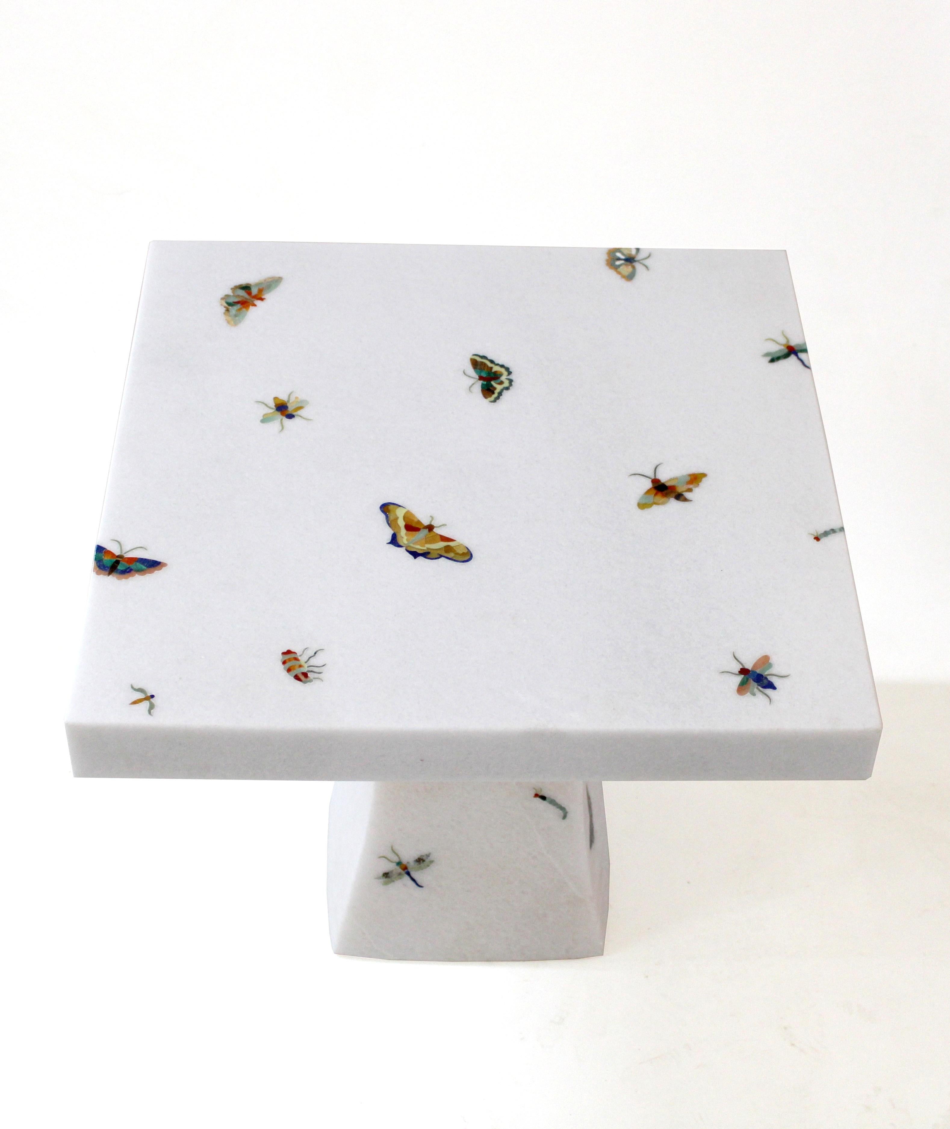 La table papillon fait partie de la collection Ornamenti. Des morceaux délicatement taillés d'agate, d'œil de tigre, de nacre et d'autres pierres semi-précieuses sont façonnés en motifs de papillon et soigneusement incrustés dans la pierre de base