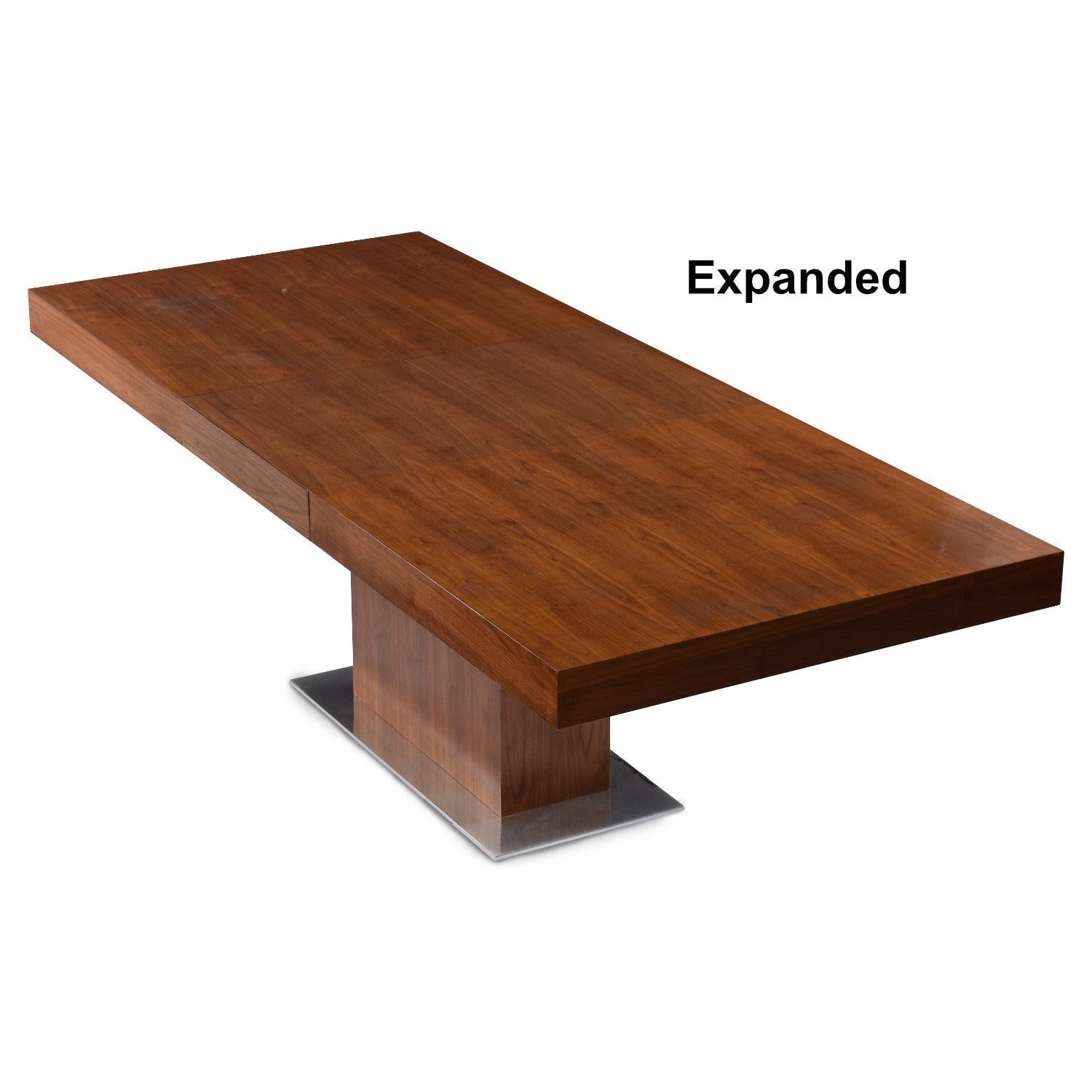 Expanding Modern walnut dining table with self-stowing butterfly leaf at center. This table is ideal for use as a conference table or dining table. The sleek design finds itself at home in a number of settings. The minimalist table has a pedestal