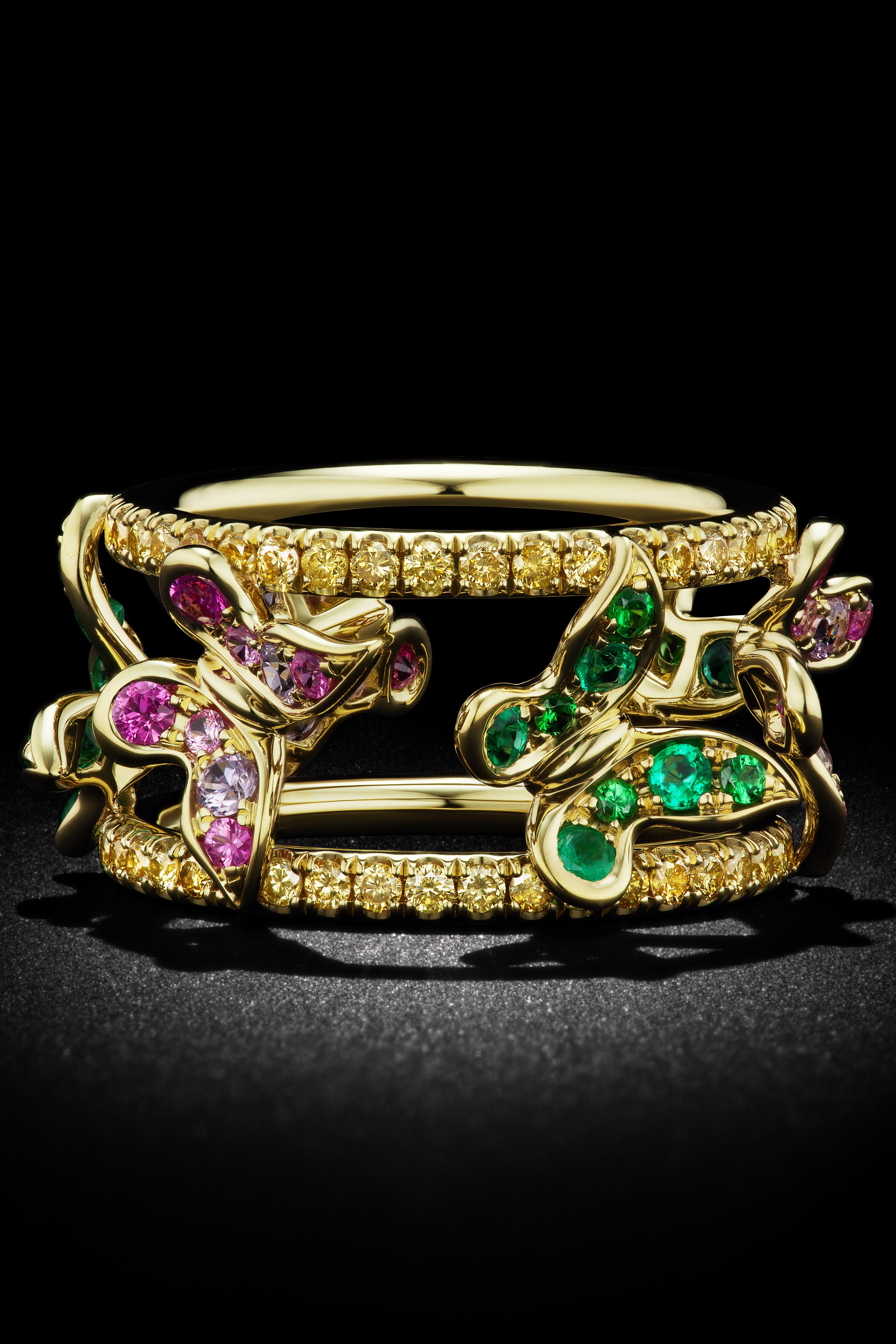 Set in 18K Yellow Gold this open frame band has butterflies comprised of Green Tsavortie, Green emeralds, Purple and Pink Sapphires with 82 yellow diamonds. 
