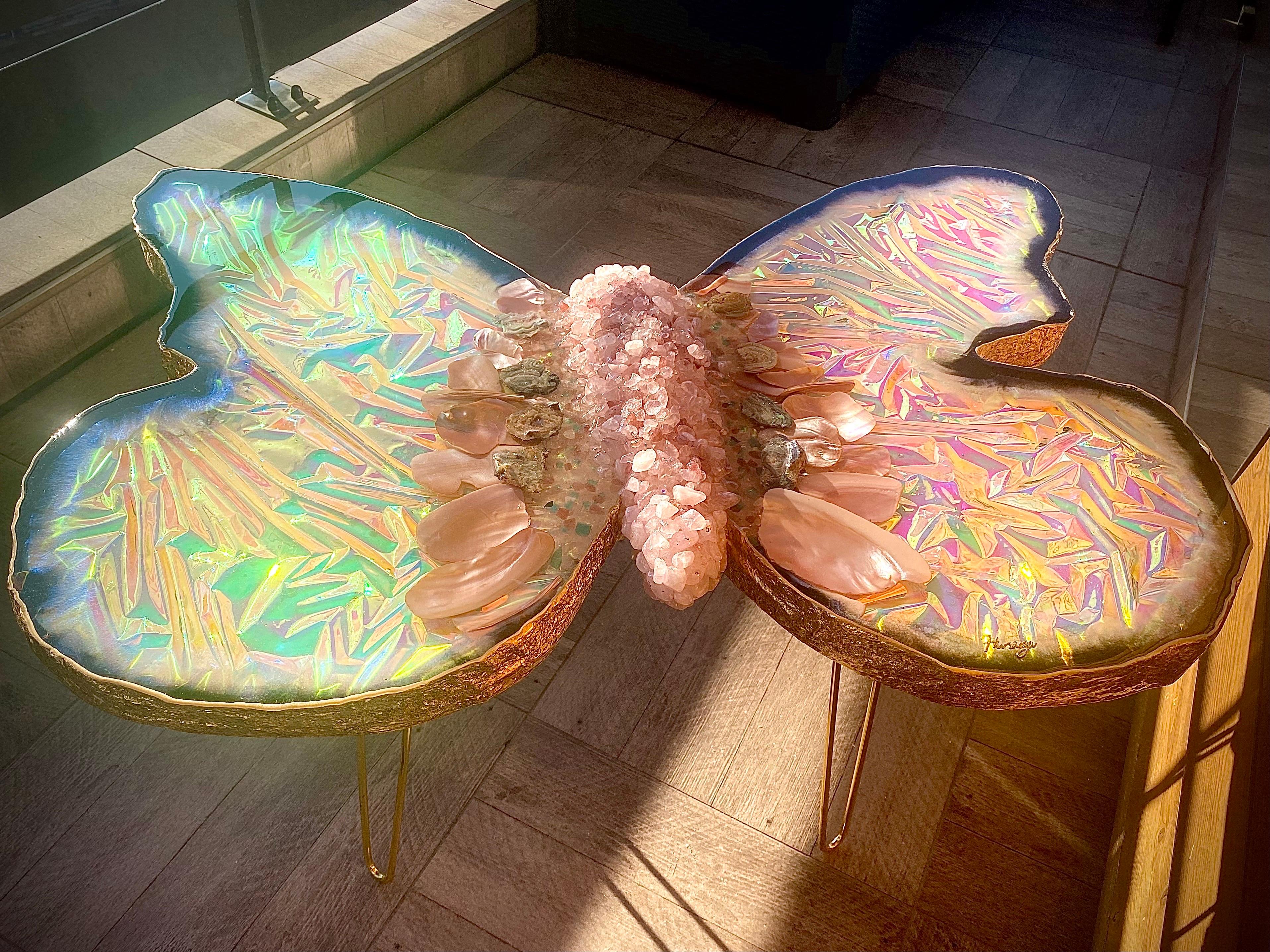 🦋 ¡Te presentamos una mesa con geodas en forma de mariposa! Es una mezcla de elegancia y naturaleza. ¡El efecto holográfico añade un toque de ensueño que se transforma con la luz! El cuarzo rosa, el cuarzo fresa, el cuarzo aura y las conchas de