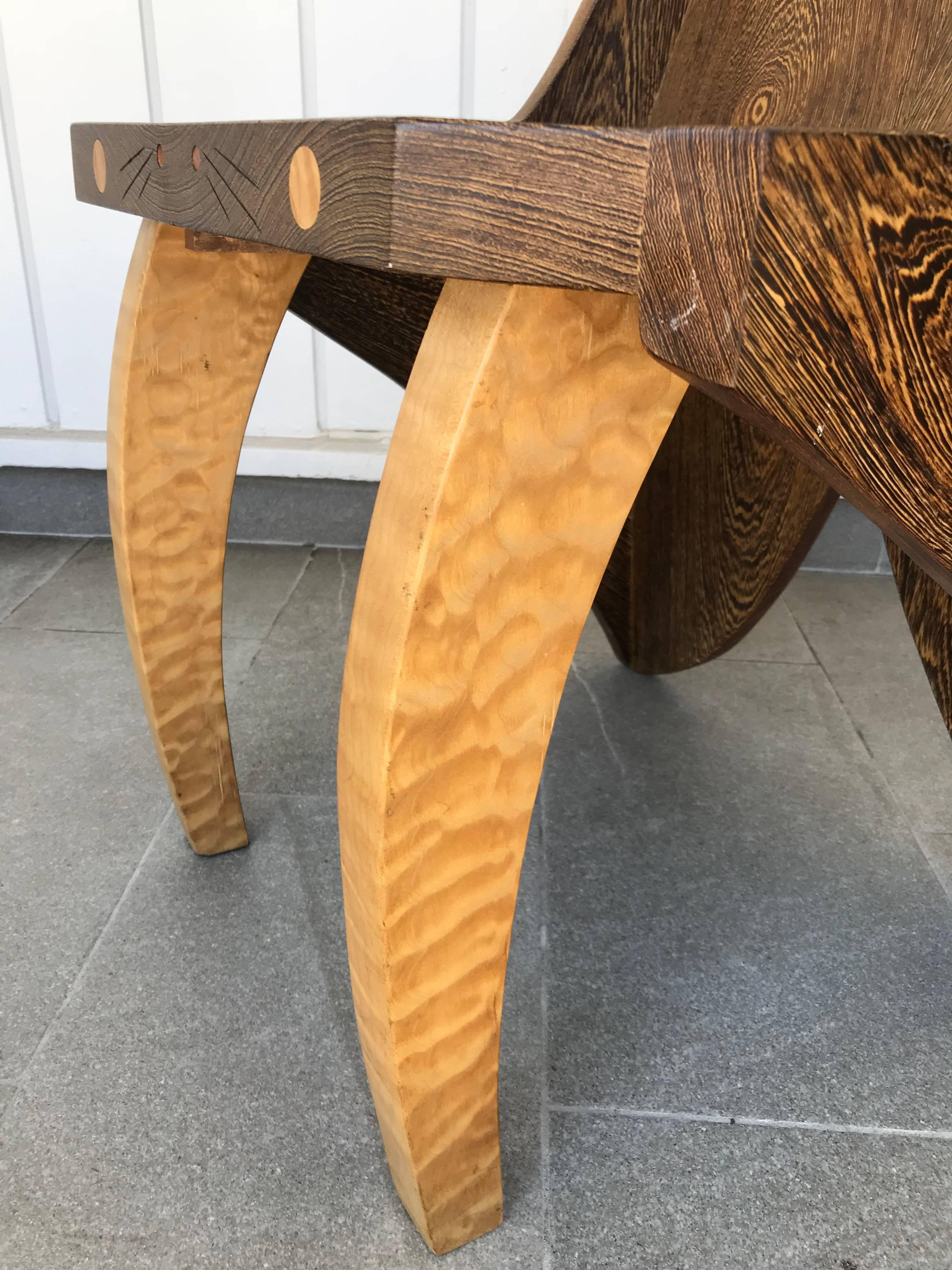 Uniquely designed chair in the shape of a butterfly, signed by artist Reid.
It's made of solid wenge and zebrawood. Beautiful details like the 4 dots on the front of the seat and the carvings between them.
This chair is a perfect statement for an