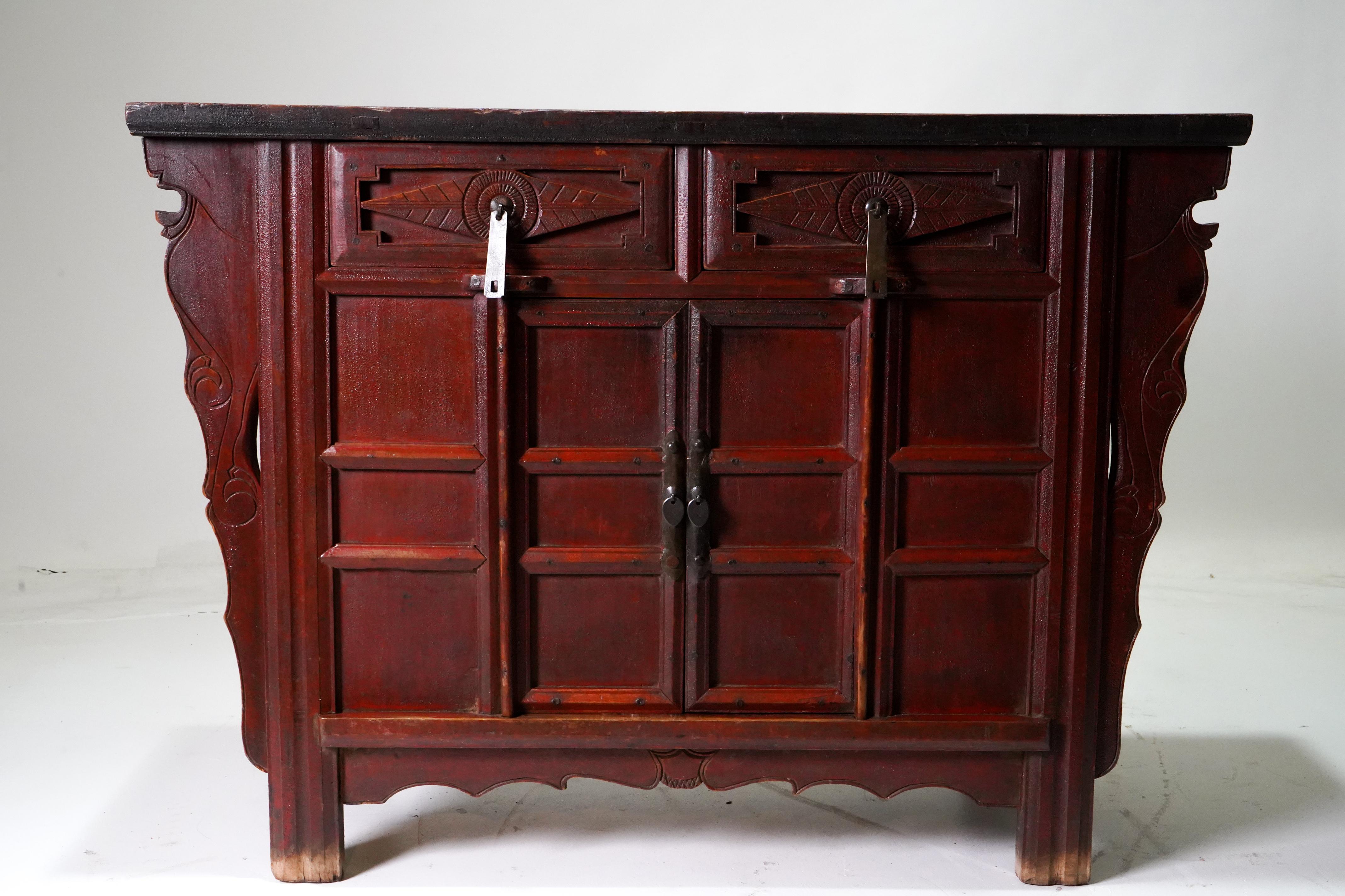 A Chinese Late Qing wooden storage chest from the 19th century, with carved spandrels, drawers, doors and finished in oxblood and cinnabar lacquer. This elegant coffer, sometimes called a butterfly cabinet, features a rectangular floating panel top