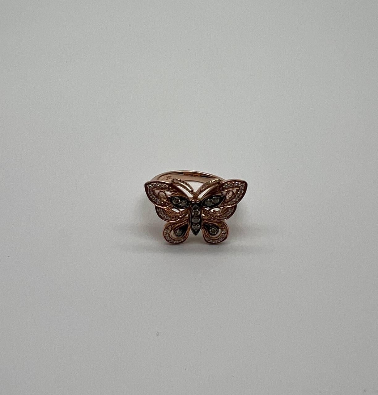 This elegant ring features a butterfly design crafted in 14K rose gold. The wings are intricately detailed with white diamonds, adding a touch of sparkle and sophistication. The butterfly's body is adorned with additional diamond accents, enhancing
