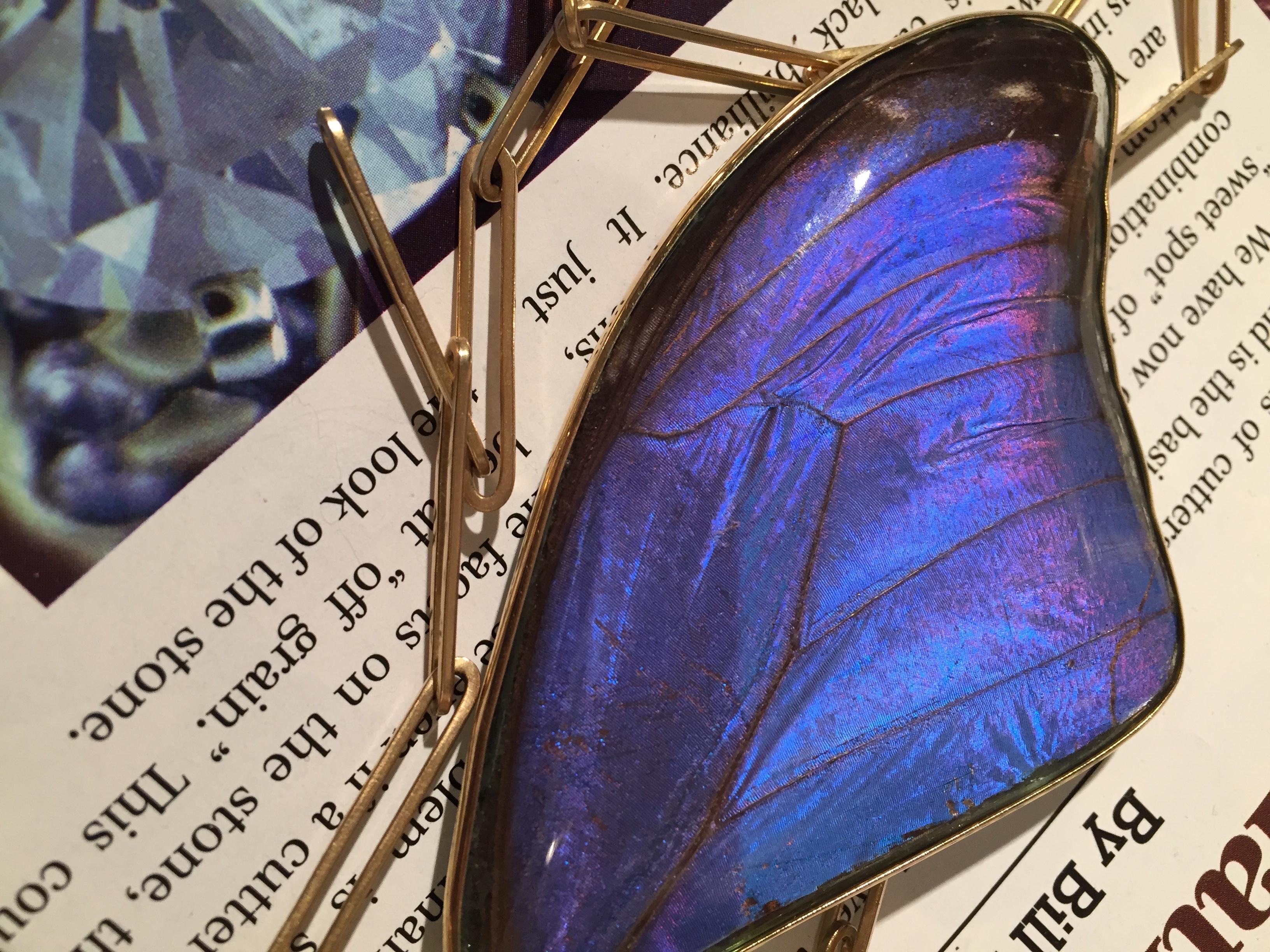 Designed as a pair of blue morpho butterfly wings, encased under optical glass, set within an 18K gold frame, suspended from a handmade 18K gold 32.5 inch paperclip chain.

Description:
Inspired by the Victorians and their use of the natural world