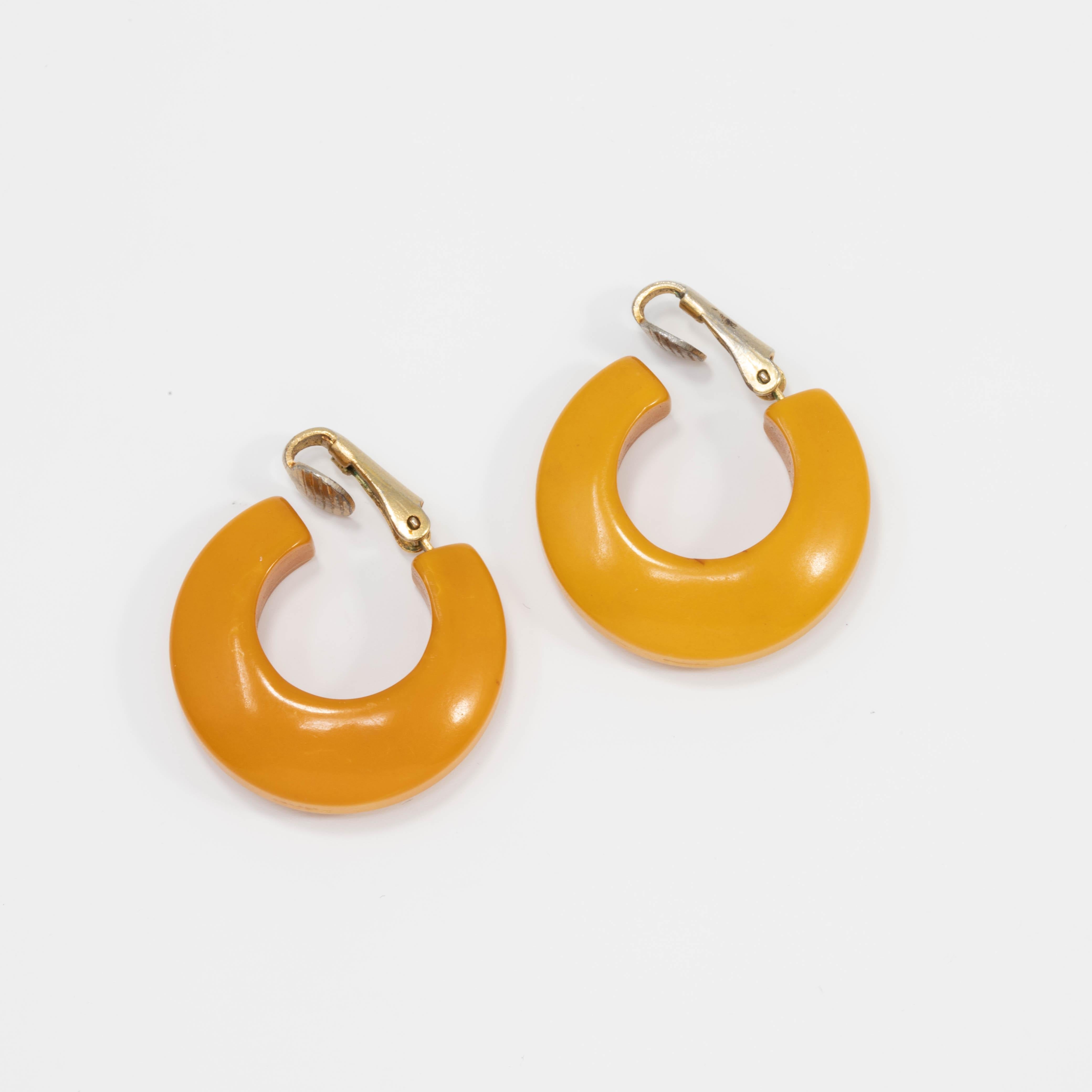 A pair of bright butterscotch yellow huggie earrings. Vintage bakelite with goldtone clip on findings.

Circa early to mid 1900s.