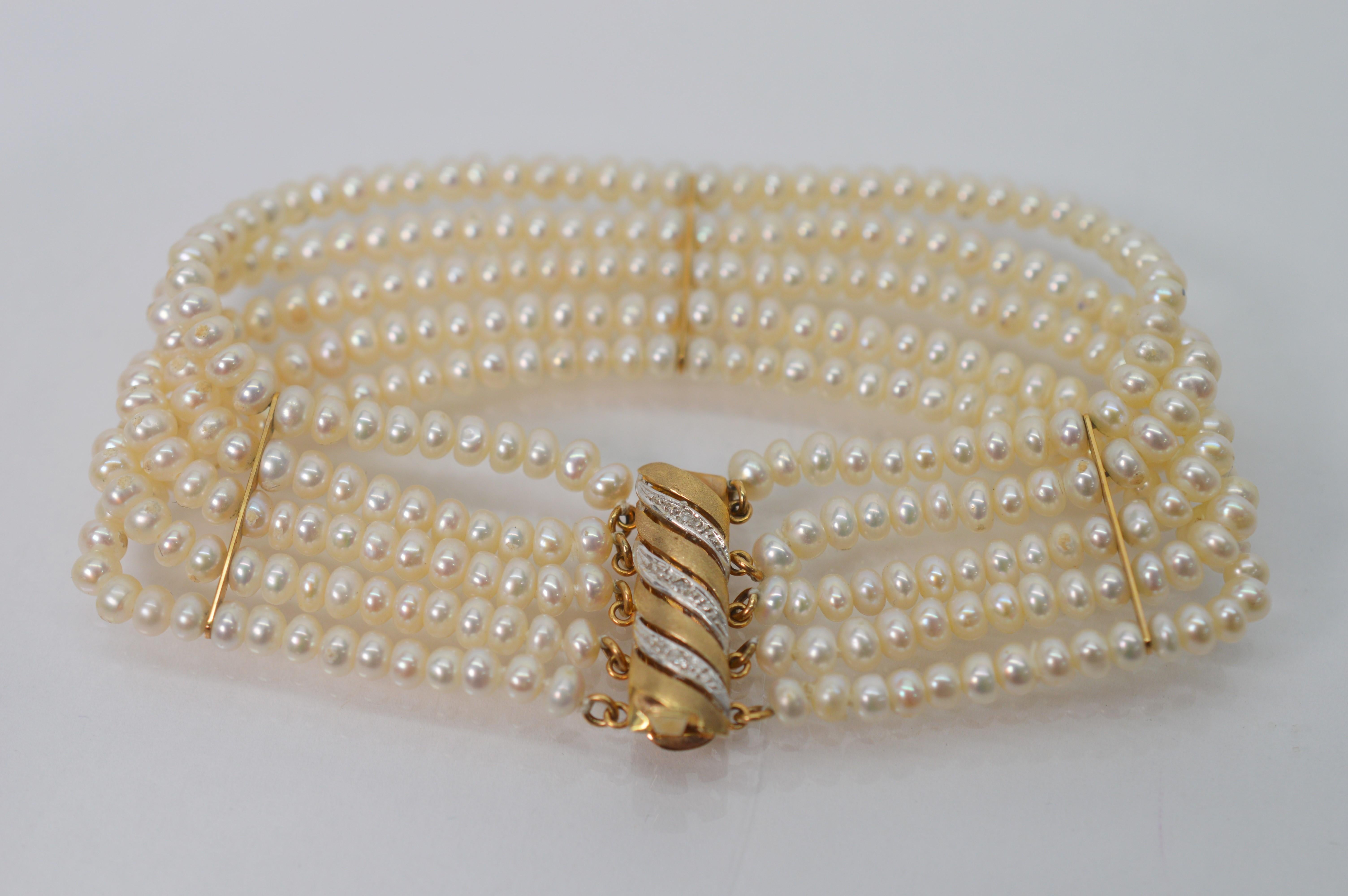 Finished with a beautiful and stylish stylish fourteen carat (14K) satin yellow gold charm clasp enhanced with swirls of diamonds, this multi-strand bracelet of lustrous 3.5mm button Akoya pearls is an elegant piece for any dress occasion. With five