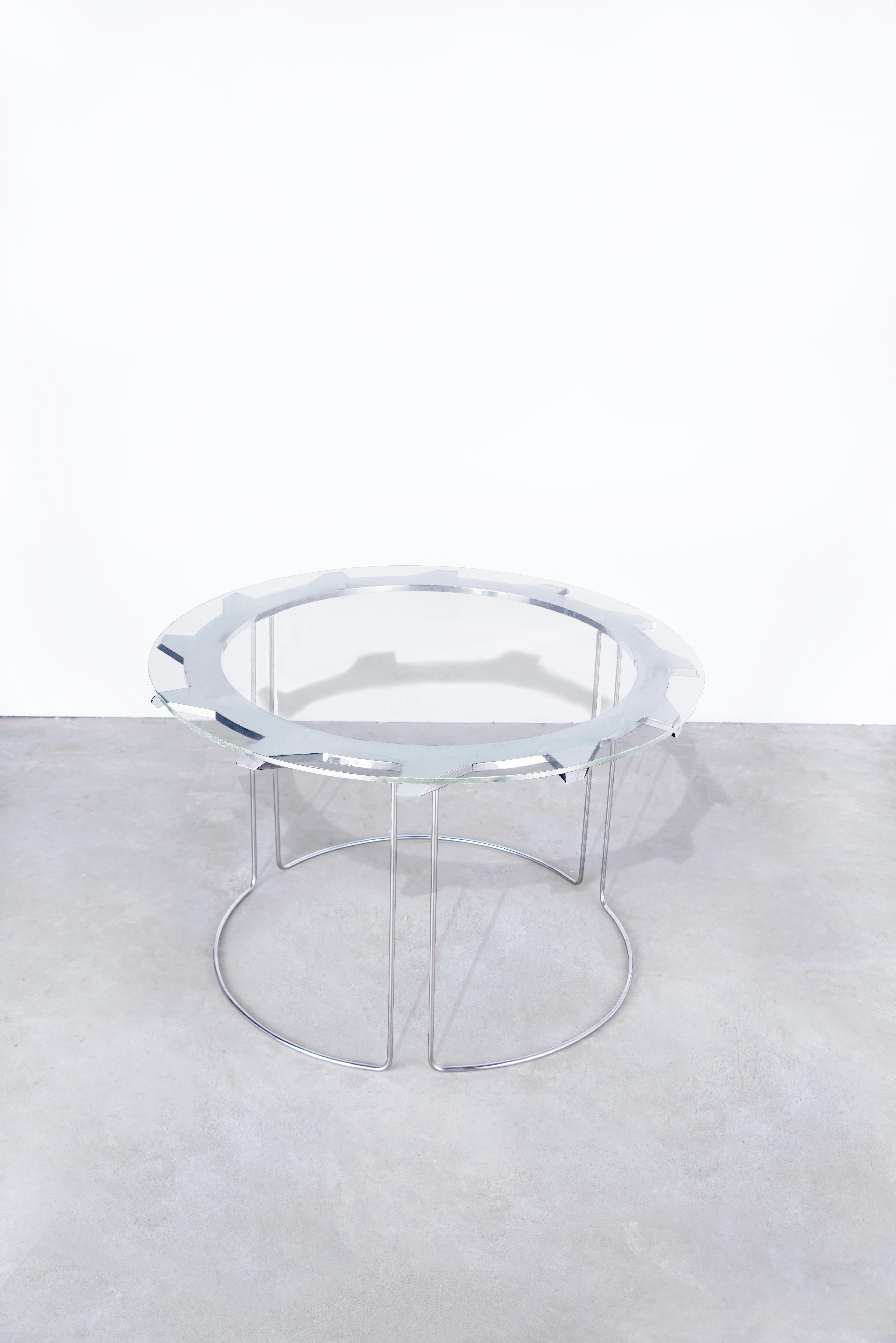 DESCRIPTION
Water jet cut + beveled, aerospace-grade aluminum. 
Hand-formed, with hand-polished stainless steel legs, welded into one continuous table base.
Starphire glass top. 
Position alone, or nest with another buzzsaw table, or buzzsaw end