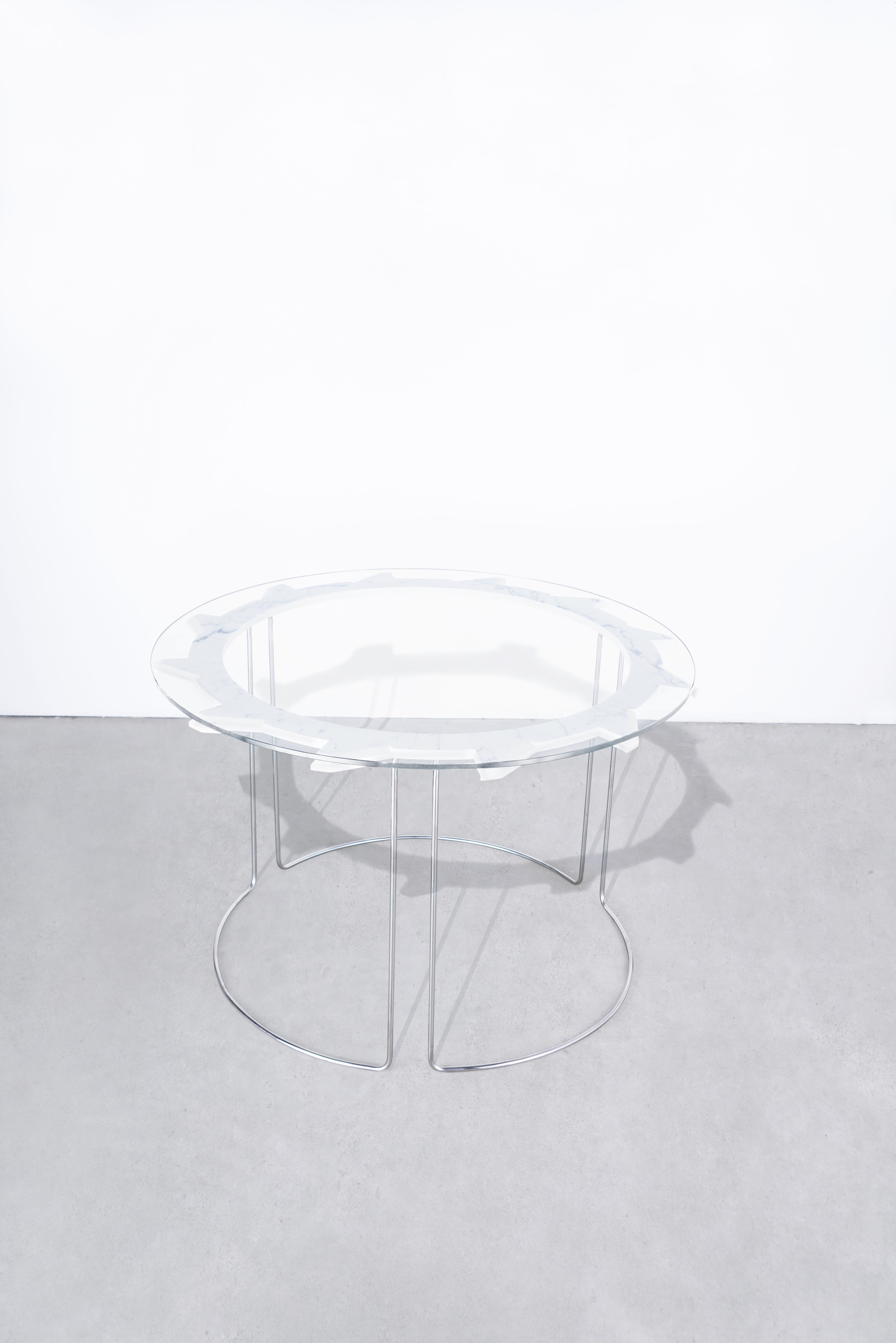 DESCRIPTION
Water jet cut, hand-beveled + hand-polished carrara marble table, with tempered glass top. 
Hand-formed + hand-polished stainless steel legs, welded into one continuous table base.
Starphire glass top. 
Position alone, or nest with