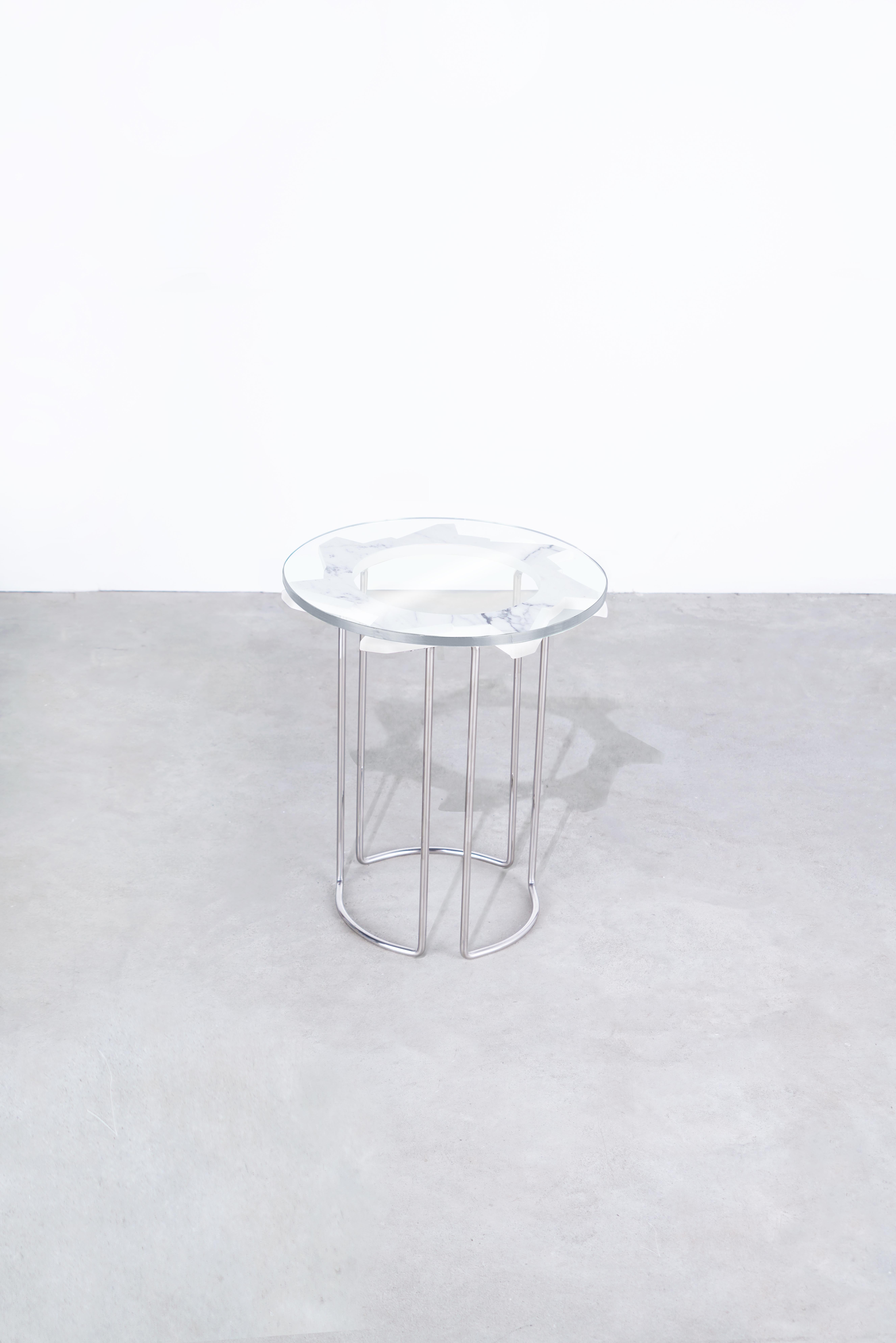 Water jet cut, hand-beveled + hand-polished carrara marble table, with tempered glass top. 
Hand-formed + hand-polished stainless steel legs, welded into one continuous table base. 
Starphire glass top. 
Position alone, or nest with another