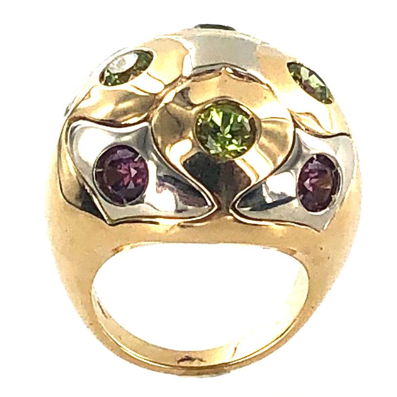This stylish dome ring by Bvlgari is fashioned in two tone 18 karat gold. The ring is adorned with 4 round cut peridot and 4 round cut pink tourmaline gemstones. The ring measures 20mm in width and 10mm in height. Currently size 5.5, but can be