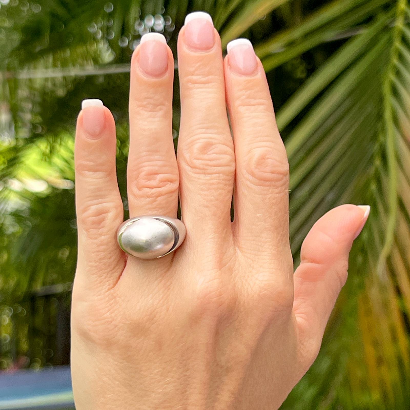 Sleek and simple designed dome ring by Bvlgari. The ring is fashioned in 18 karat brushed finish white gold. Domed on top with two cut outs to add dimension, the wide shank tapers from 14.5mm to 3.5mm. The ring is size 52 (US size 6). 
