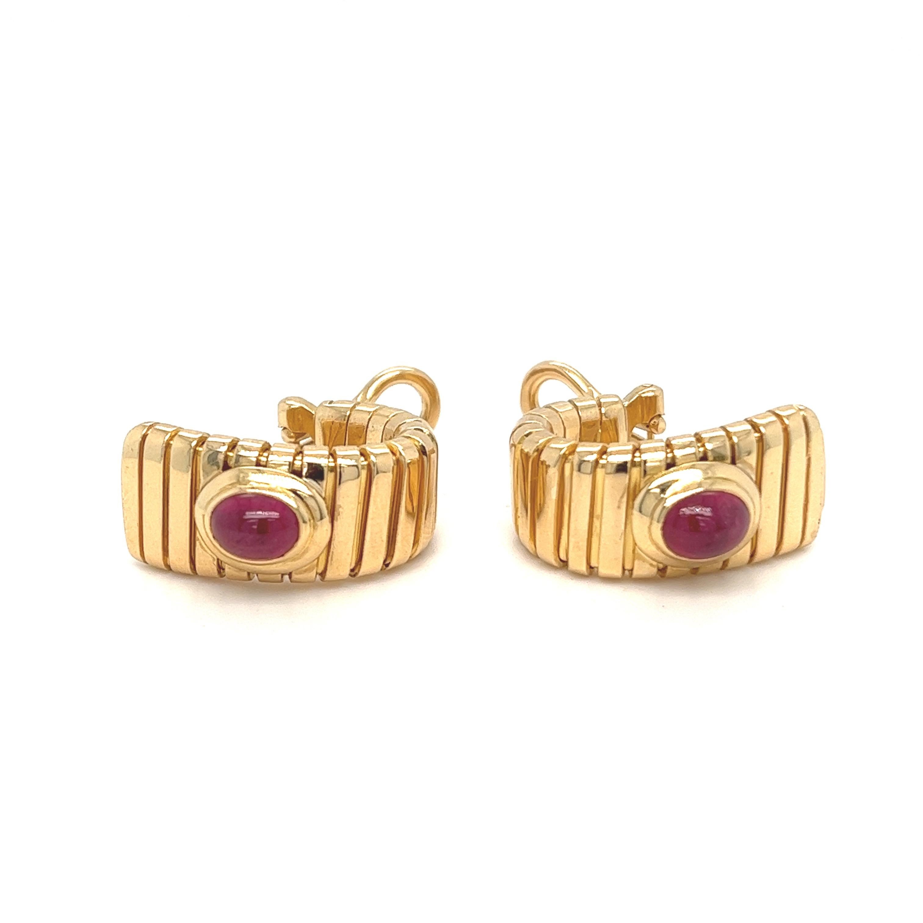Casual chic pair of 18 karat yellow gold and ruby Tubogas half hoop earrings by the Italian brand Bvlgari, 1990s.
Crafted in 18 karat yellow gold, each set with an oval ruby cabochon of circa 0.6 carats, these earrings are completed by comfortable