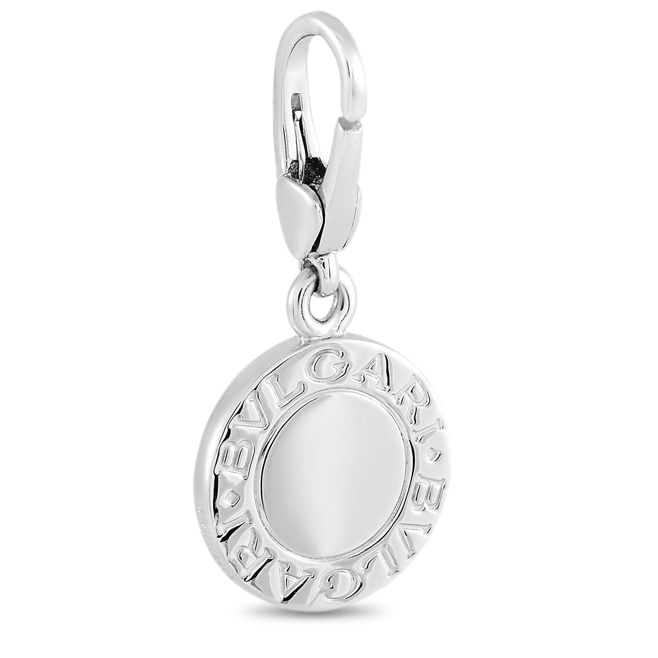 This Bvlgari 18K White Gold Charm is a must have! The pendant is made from 18K white gold and is set with a flat blue stone in the center. The pendant features the Bvlgari brand name along the outer edge on both sides. The pendant measures 1.15