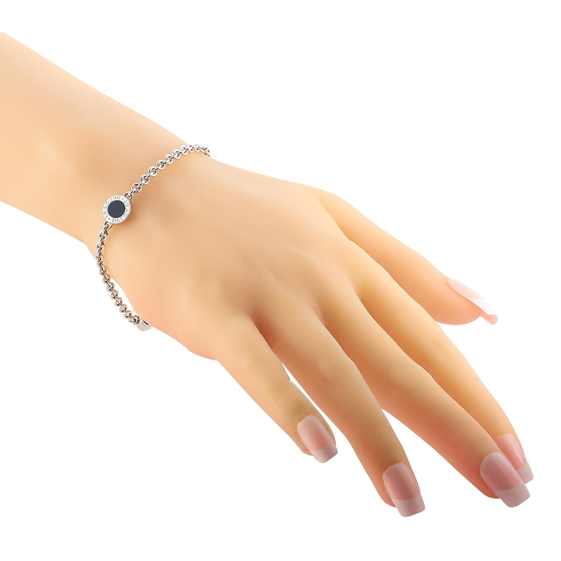 This Bvlgari bracelet has a beautifully minimalist point of view. Crafted from glistening 18K White Gold, it features a trio of bezel-set onyx stones surrounded by a metal halo featuring the luxury brand’s logo. It measures 7” long and features