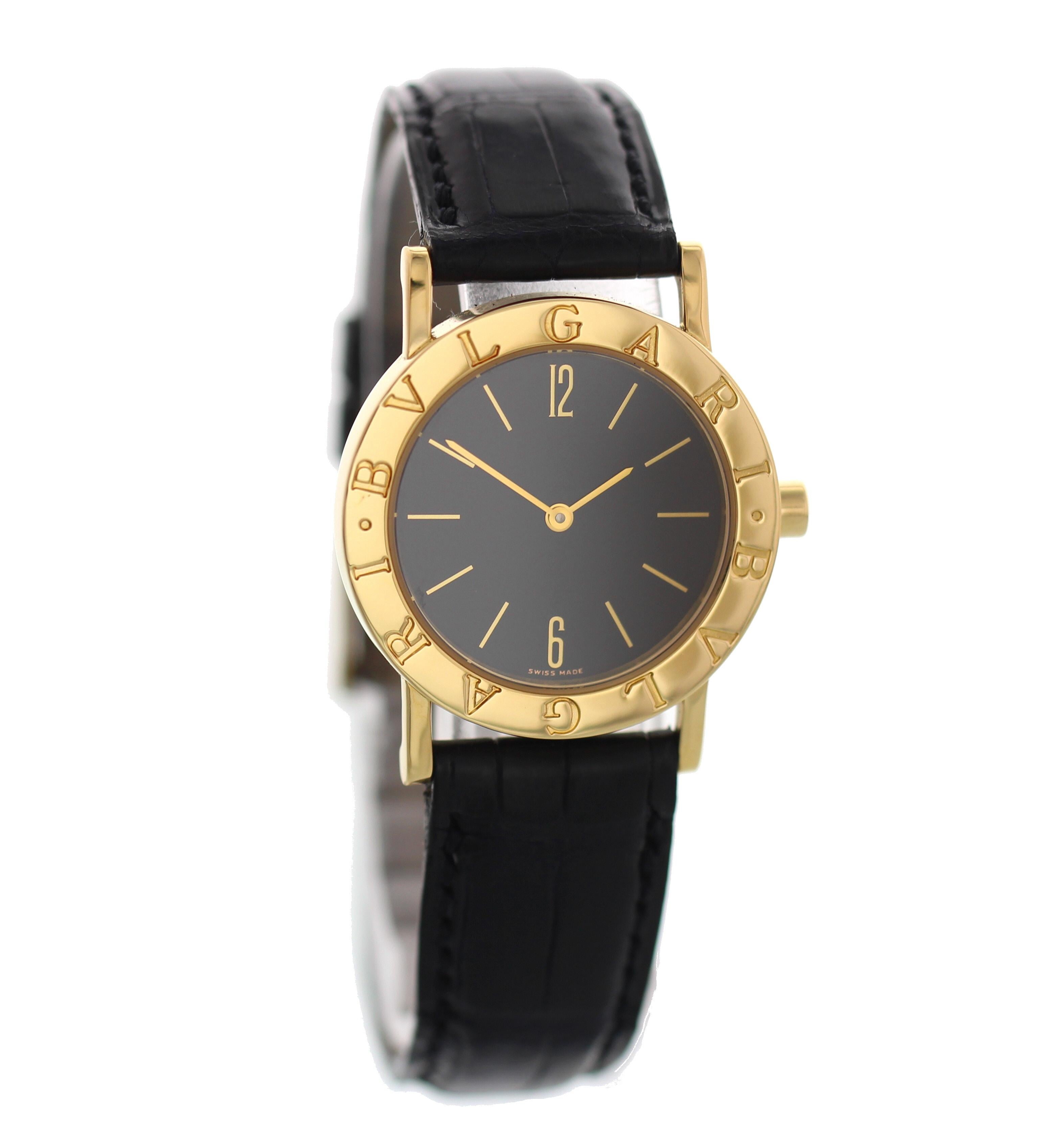 Ladies midsize Bvlgari gold watch. 18k yellow gold 30mm case with 'BVLGARI' engraving. Black dial with gold indexes and hands. Black leather Bvlgaristrap with an 18k yellow gold buckle.  Quartz battery movement. 

This watch is backed by our one