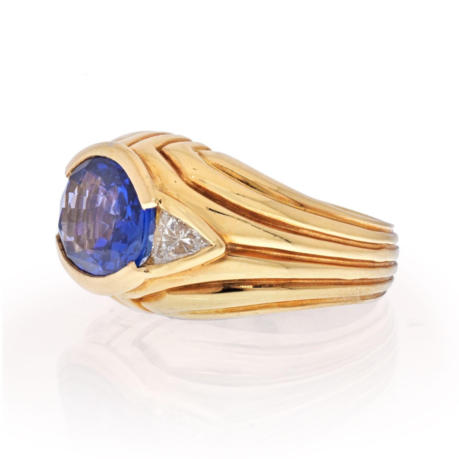 Vintage sapphire and diamond cocktail ring by Bvlgari. Mounted in 18k yellow gold the ring features a 4.50 carat (approx.)  oval cut blue sapphire flanked by two trilliant cut diamonds. 