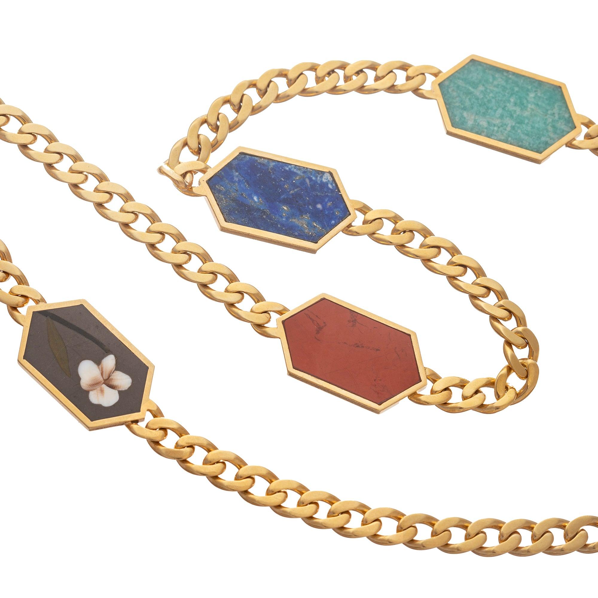 1970's long necklace in 18k yellow gold, designed as a long curb link-style gold chain necklace with six bezel-set reversible hardstone links.  Hexagonal panels each inset with a different flower motif on one side and the reverse side inset with a