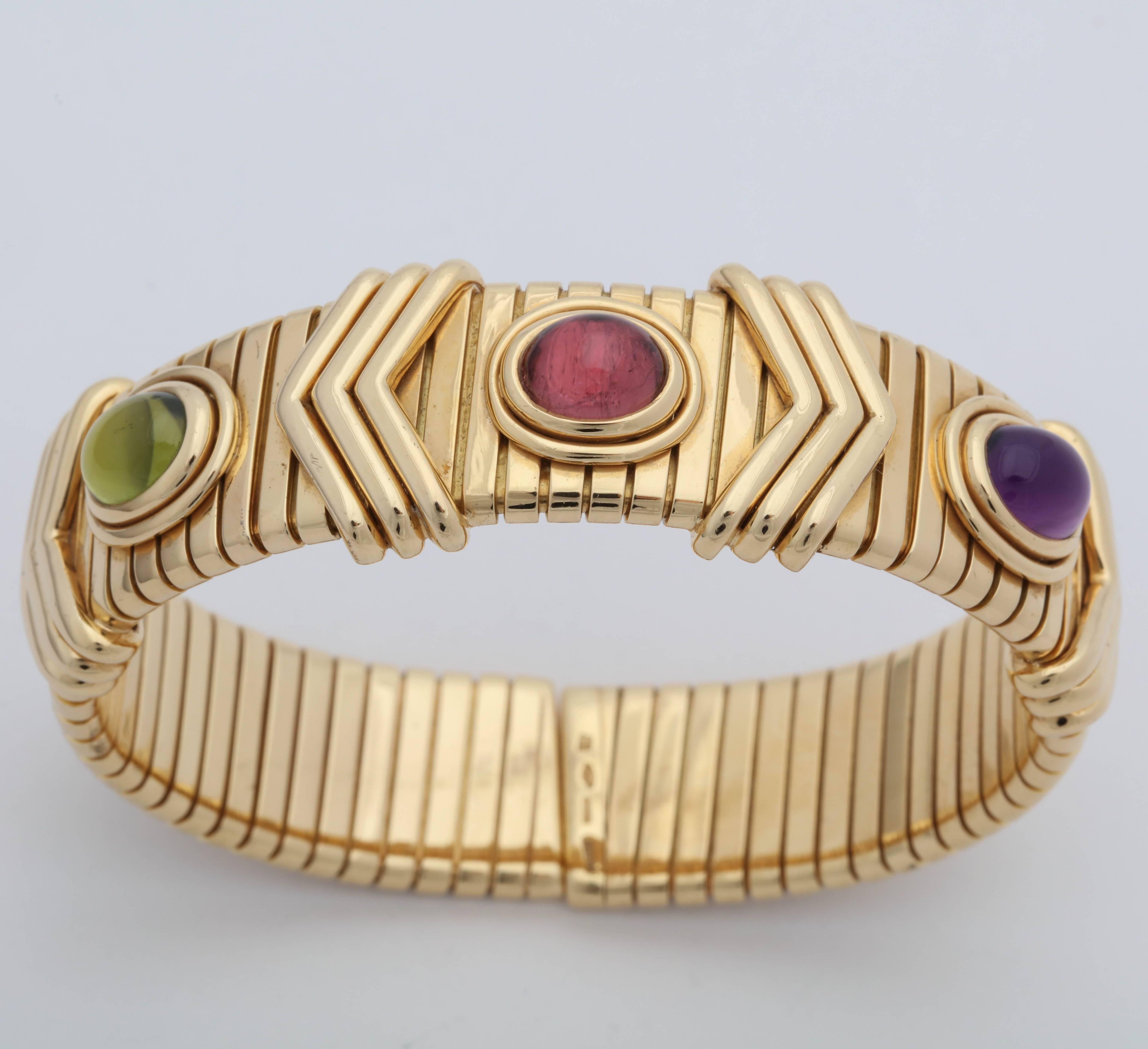 One Bulgari Flexible Cuff Bracelet, Omega Style Created In  18kt Yellow Gold. Bracelet Is Further Embellished with Three Cabochon semi-Precious Stones consisting of One 6MM Pink Tourmaline In The Center And One 6MM Cabochon Peridot Stone And Lastly