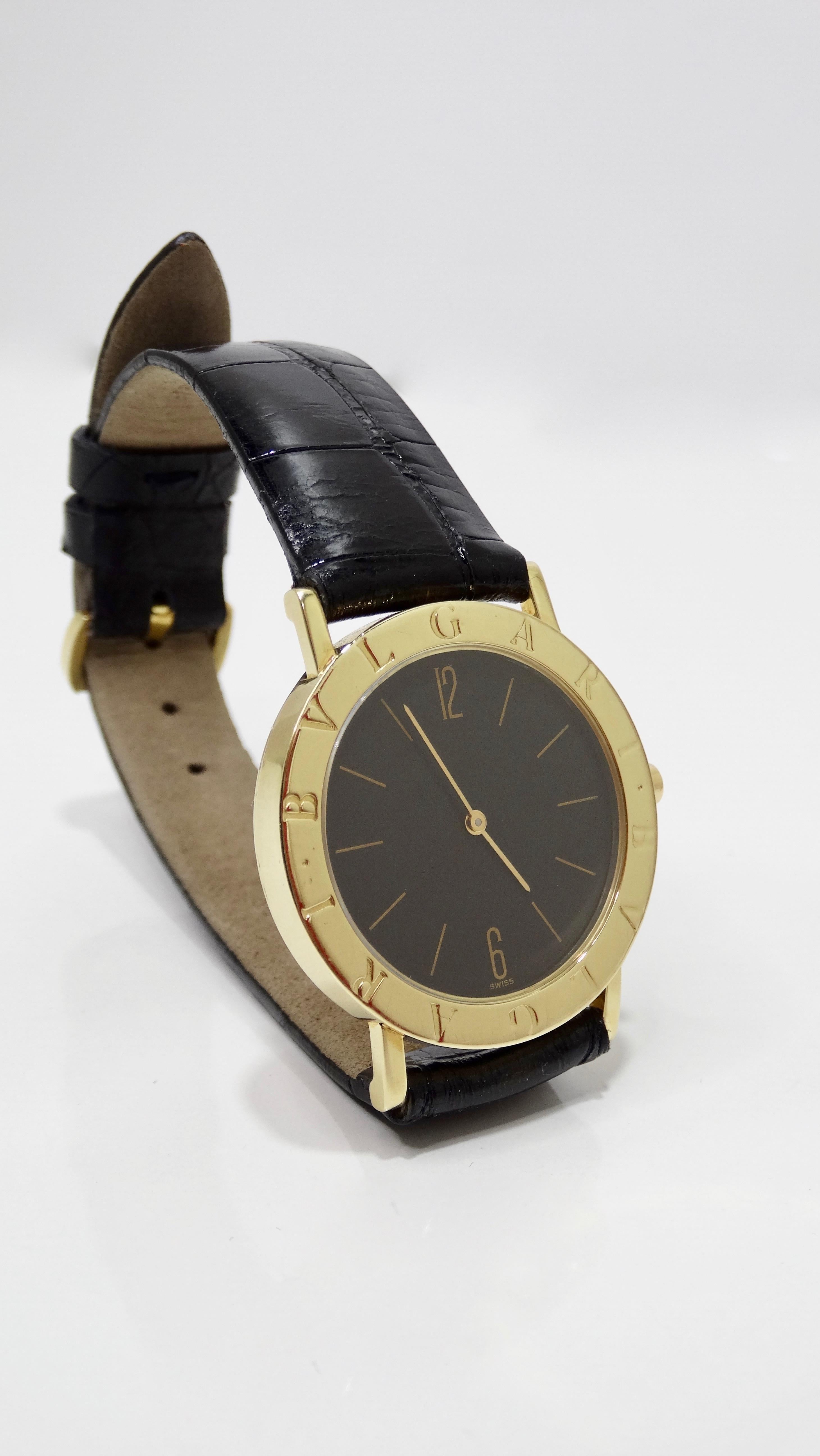 Circa 1990s/ early 2000s, this round 33mm Bvlgari wrist watch features an 18k gold case with a Bvlgari engraved bezel, a mineral glass crystal face, and a matte black dial with gilded gold time markings. Watch includes quartz movement, a stamped