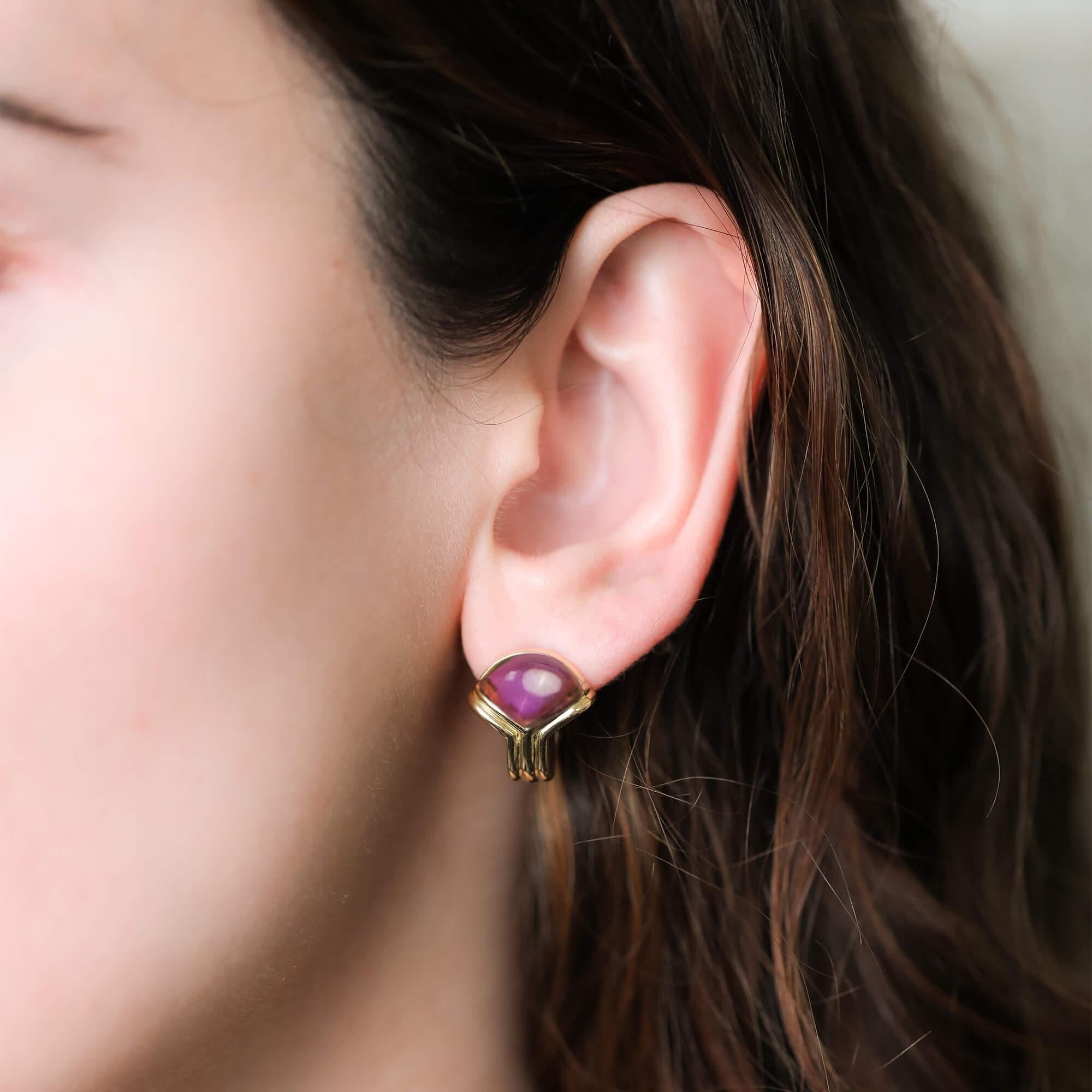 This pair of late 20th century earrings by designer Bvlgari are crafted in 18k yellow gold and feature their signature design domed mount, set with triangular cabochon cut amethyst and peridot gemstones surrounded by double ribbed bezel setting.