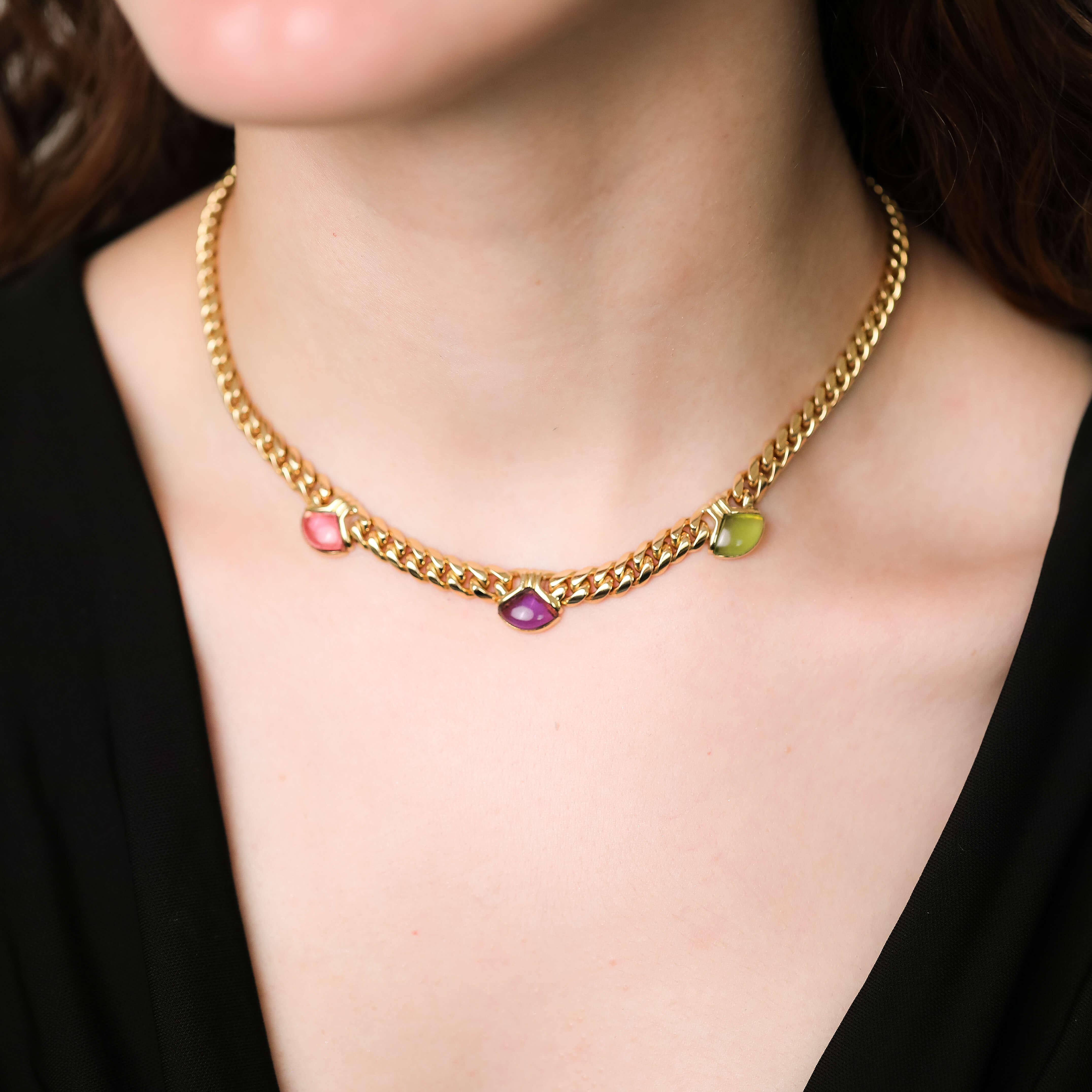 This late 20th century necklet by designer Bvlgari are crafted in 18k yellow gold and feature their signature design, set with triangular cabochon cut amethyst, peridot and pink tourmaline gemstones surrounded by double ribbed bezel setting upon a