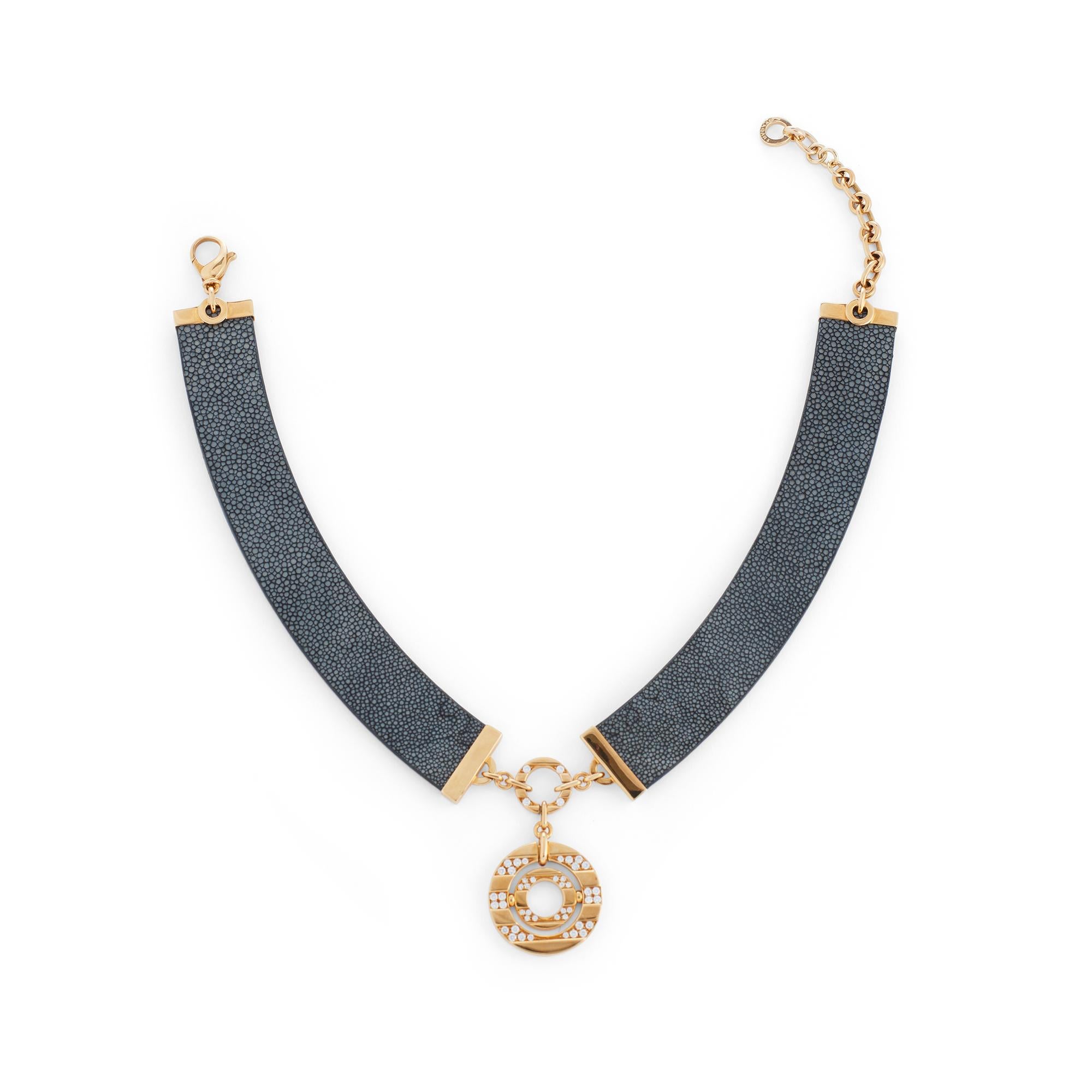 Authentic Bvlgari Astrale pendant necklace crafted in 18 karat yellow gold.  Featuring a circular Astrale pendant accented with an estimated 1.40 carats of round brilliant cut diamonds.  The pendant is situated on a collar of gray-black galuchat