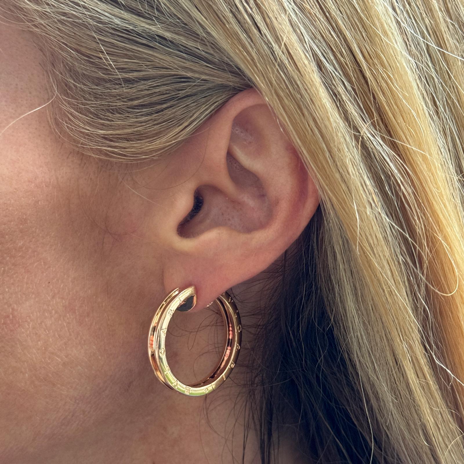 The BVLGARI B-Zero Rose Gold Hoop Earrings embody modern luxury with their sleek, iconic design. Crafted from 18 karat rose gold, these hoops feature the distinctive BVLGARI  motif, inspired by the Colosseum's architectural elegance. The polished