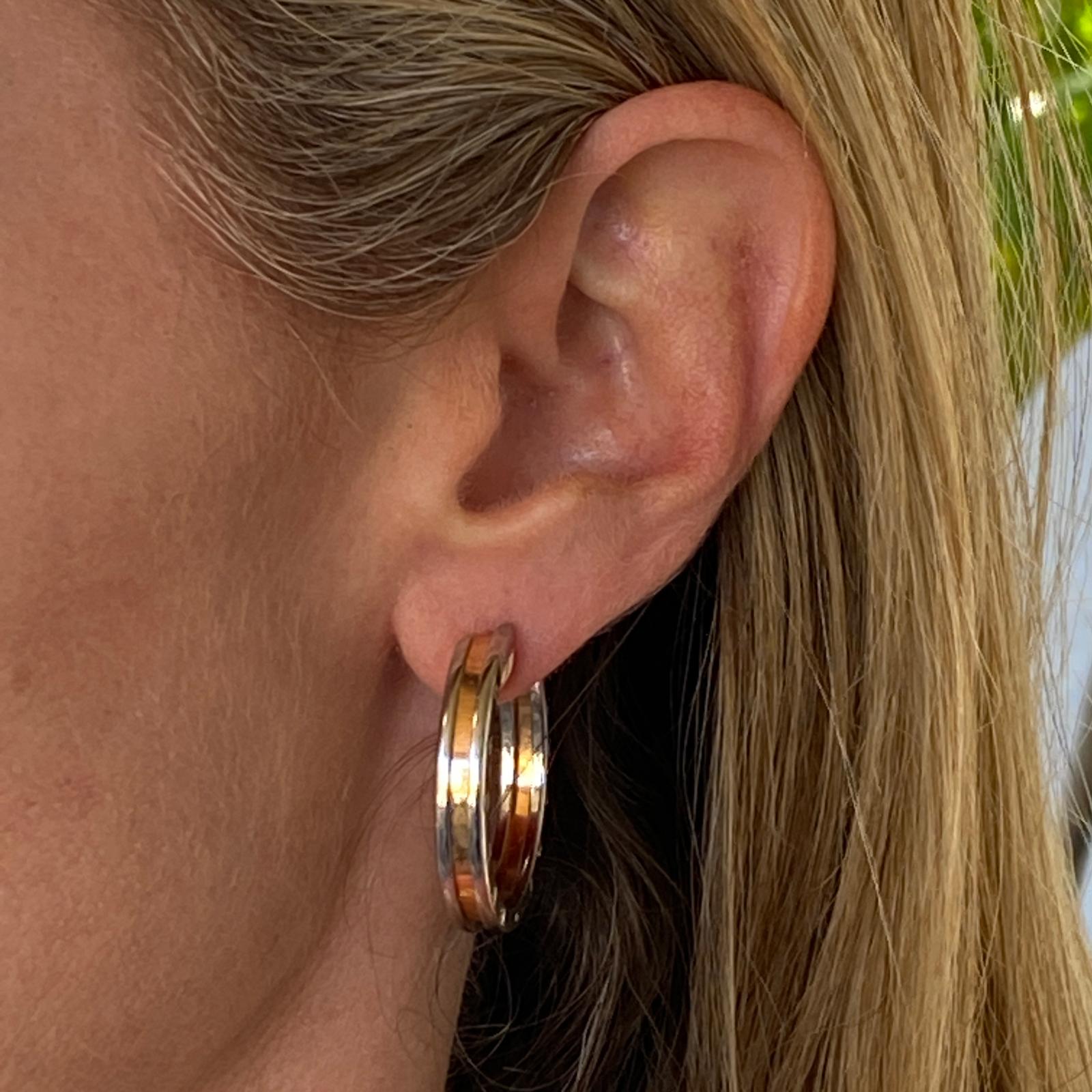 Bvlgari B.Zero1 hoop earrings fashioned in 18 karat rose gold and stainless steel. The hoops feature  the Bvlgari name, Made In Italy, and are marked for left and right ear. The hoops measure 30mm in diameter. 