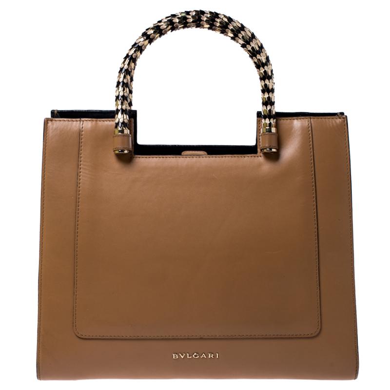 Bvlgari's Serpenti collection has stunning creations and this tote is a fine example. Crafted from beige leather, the Serpenti Scaglie tote is styled with retractable snake handles and black leather panels on the sides. The bag comes with a spacious