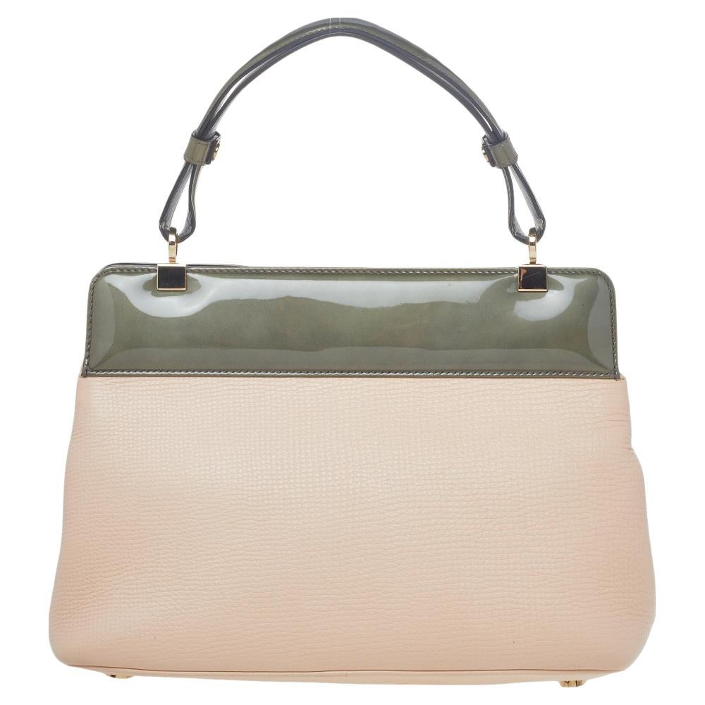 This Isabella Rossellini bag from Bvlgari is crafted from beige & grey leather and patent leather and has a refined design. The bag comes with protective metal feet and a top handle. The turn-lock closure opens to a leather-lined interior capacious