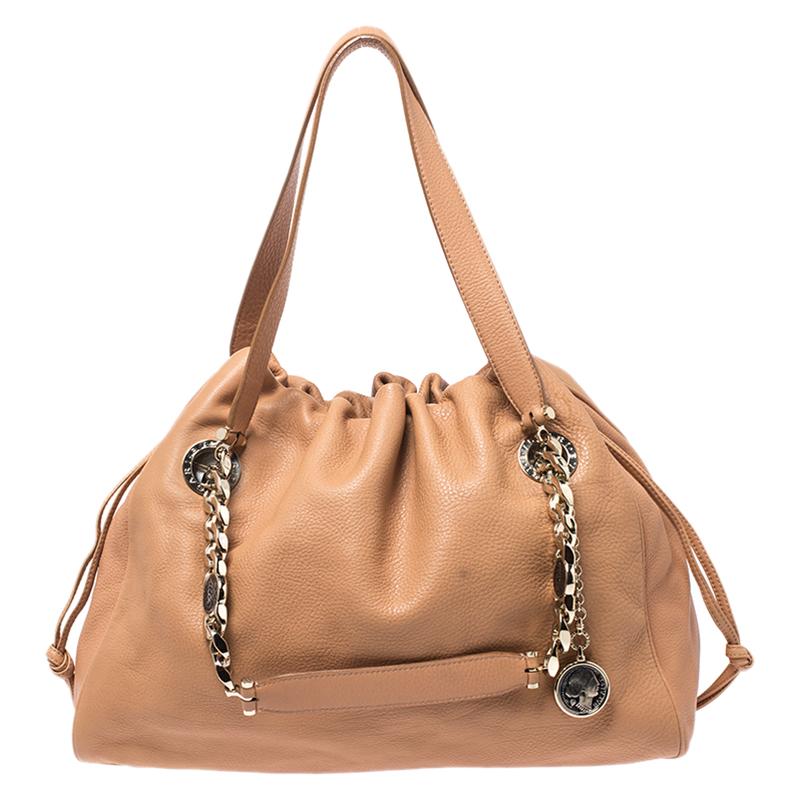 This everyday Bonton tote by Bvlgari is made from versatile beige leather. It is accented with two top handles and a chain-link strap. The interior is lined with fabric and is spacious enough to hold all your basics. The bag is complete with