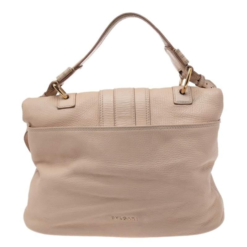 This stunning Leoni bag from the House of Bvlgari has been crafted to deliver style and functionality. Made from beige leather, it comes equipped with two top handles and a gold-toned logo motif on the front. This bag opens to reveal a spacious