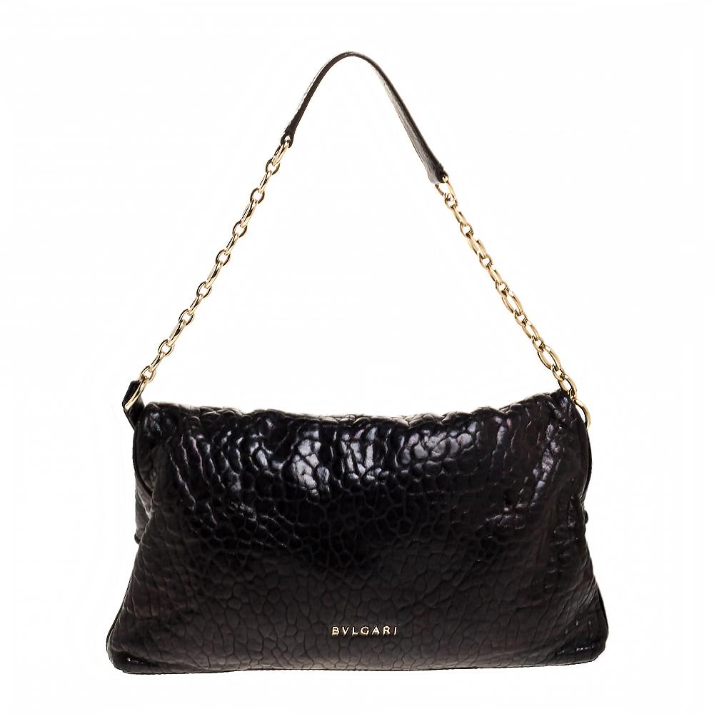This stunning bag by Bvlgari has been crafted to deliver style and functionality. Made from leather, it comes in a black color that adds glamour and interest. It comes equipped with a handle, a foldover top with a gold-tone closure with the brand's