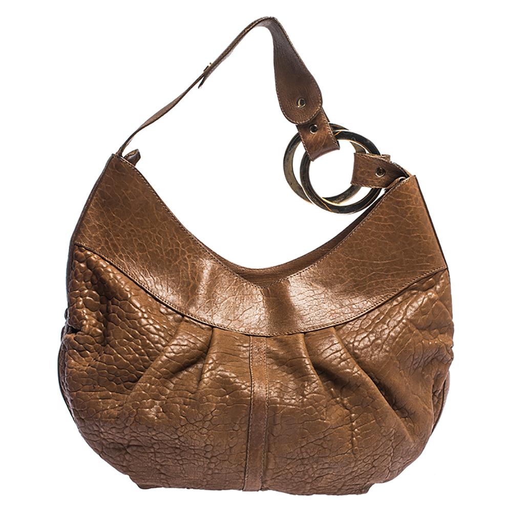 This Bvlgari hobo is stunning. Crafted from leather, it comes in a lovely shade of brown. It is styled with a single handle, a pleated exterior, and gold-tone hardware. It has a leather-lined interior with a slip pocket and enough space for
