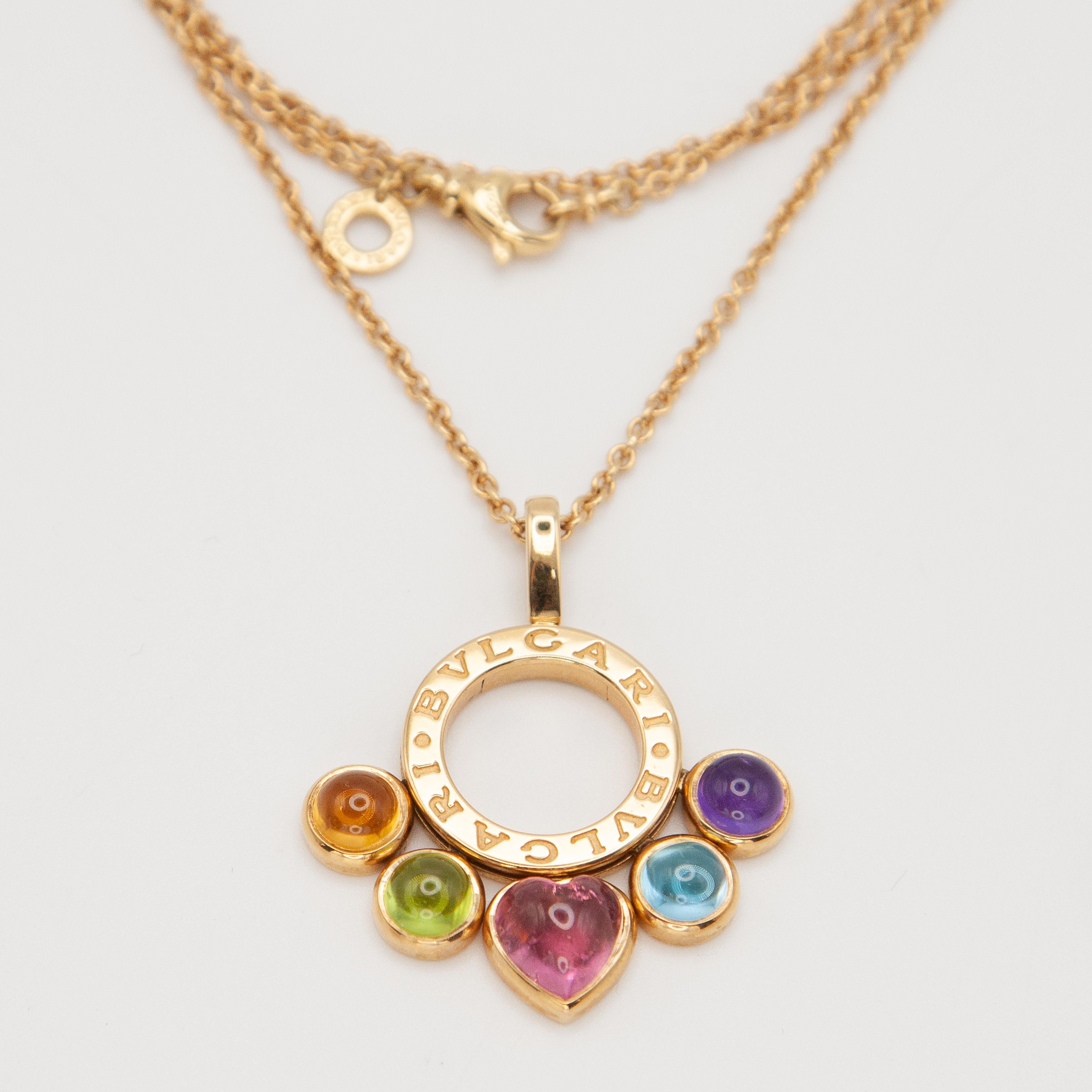 A striking Bulgari necklace crafted in 18 karat yellow gold, featuring the house’s iconic Bvlgari Bvlgari circular pendant. The pendant is set with five vibrant cabochon-cut gemstones: a heart-shaped pink tourmaline, accented by citrine, peridot,