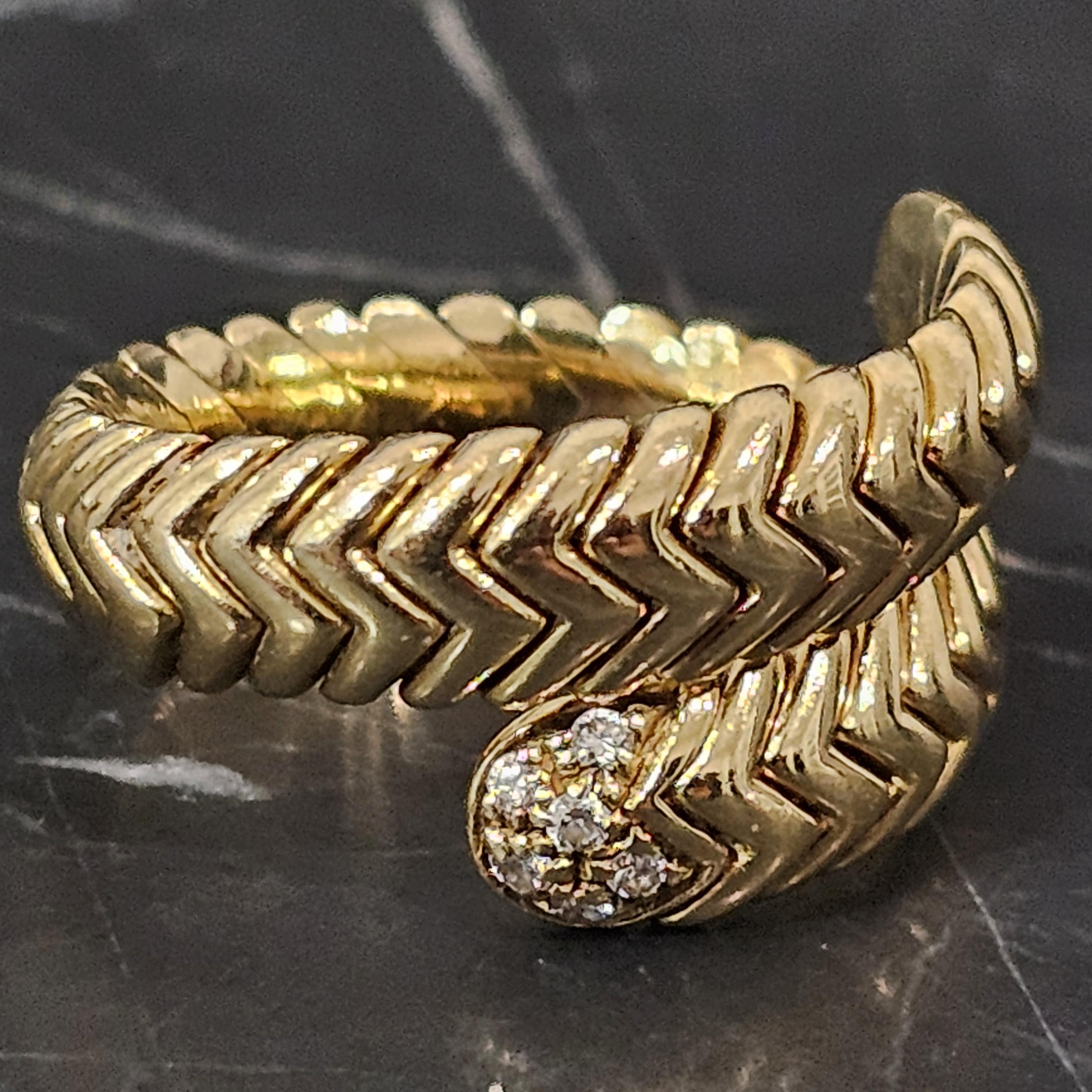 Presenting a striking Bvlgari Spiga ring, expertly crafted in 18k yellow gold. This exquisite piece features a bold chevron pattern, elegantly wrapping around the finger. The design is accentuated by a cluster of white diamonds at each end, adding a