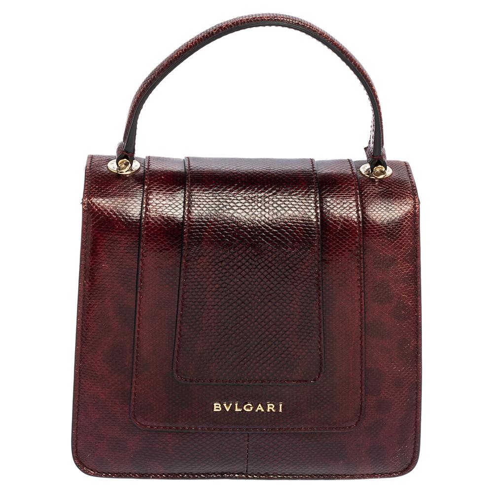 Dazzle the eyes that fall on you when you swing this stunning Bvlgari creation. Crafted from snakeskin-embossed leather in a breathtaking burgundy hue, the bag is styled with a flap that has the iconic Serpenti head closure. The bag has a spacious