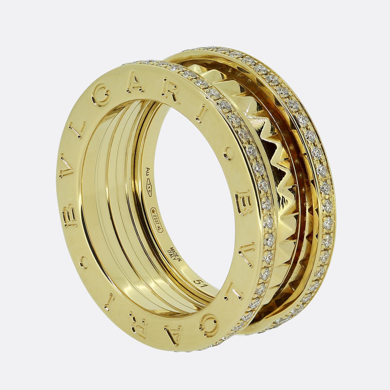 Nous avons ici une bague B.Zero1 de la célèbre maison de joaillerie italienne Bvlgari. Il s'agit d'un modèle à deux anneaux en or jaune 18ct, avec une rangée de diamants ronds de taille brillant au-dessus et au-dessous d'un centre clouté en