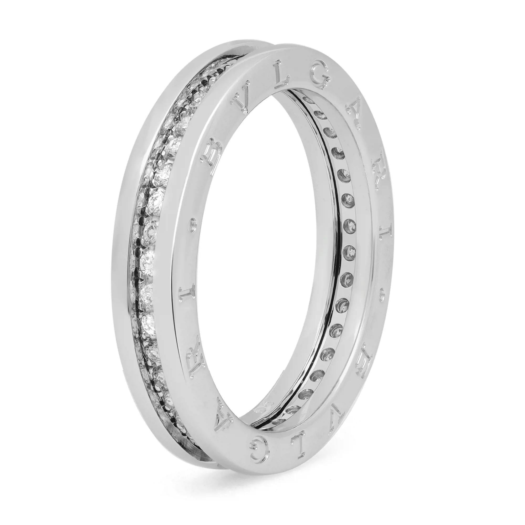 The B.Zero1 ring is a signature piece from the legendary jewelry design house Bvlgari. Crafted in fine 18K white gold. It features a clean modern one band ring with pave set round cut diamonds weighing 0.60 carat. The outer rims are engraved with