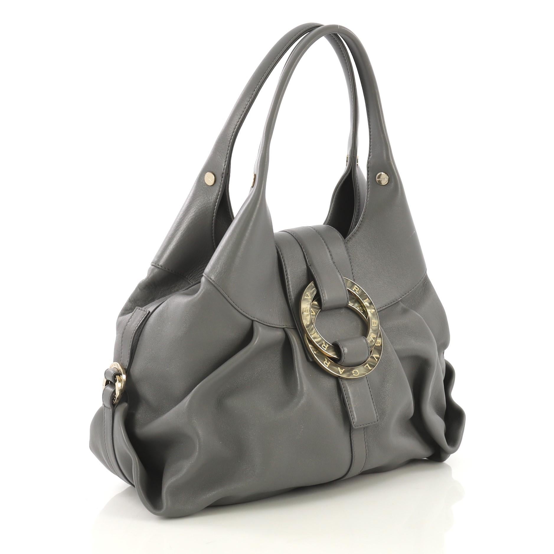 This Bvlgari Chandra Hobo Leather Large, crafted from gray leather, features dual leather handles, double metal ring details with engraved Bvlgari signature, and gold-tone hardware. Its hook closure opens to a red fabric interior with side zip