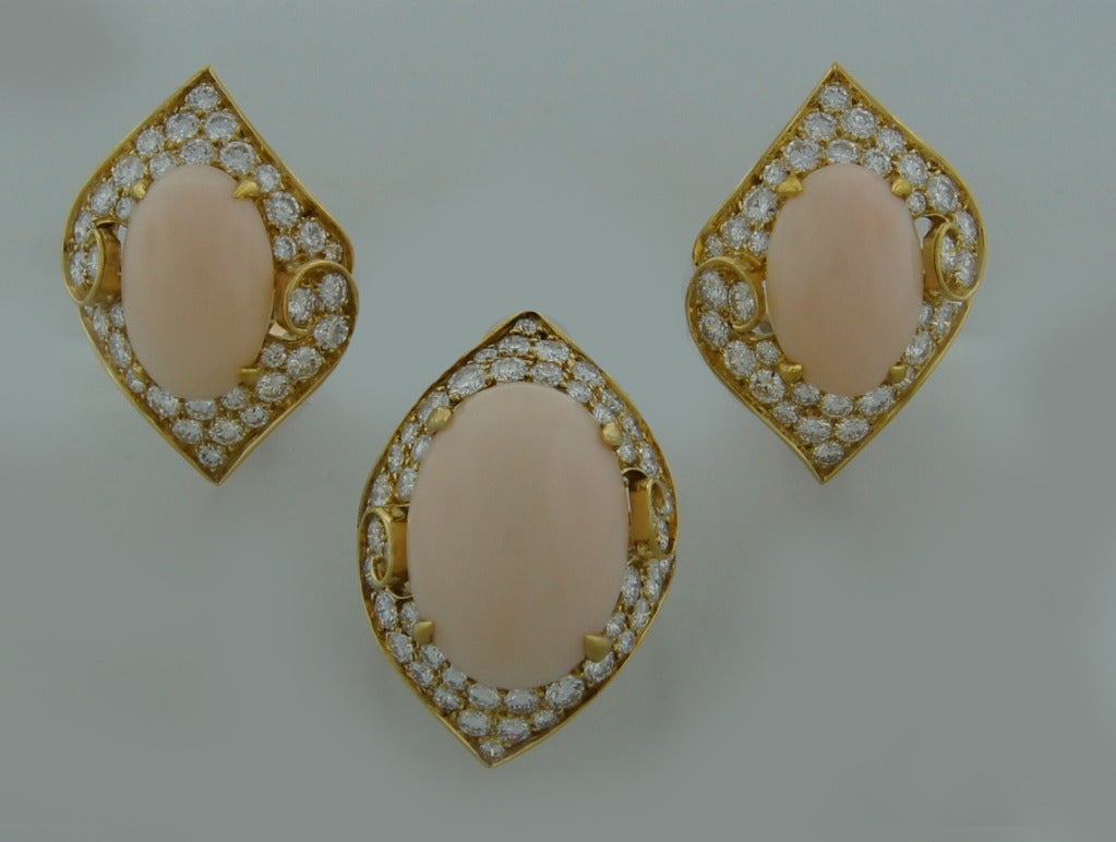 Magnificent set consisting of a cocktail ring and a pair of earrings created by Bulgari in Italy in the 1980s. Features an oval angel skin coral set in 18 karat yellow gold and framed with round brilliant cut diamonds (F-G color, VS clarity, total