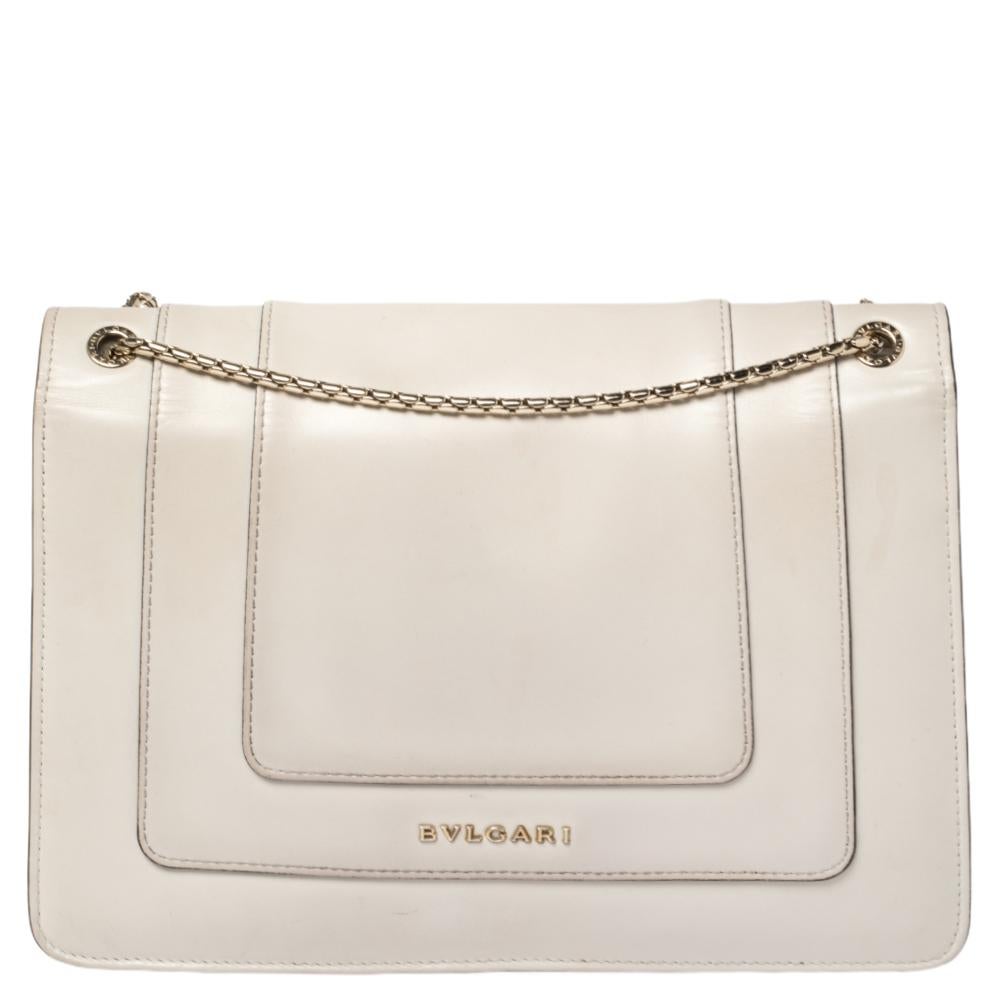 Añade un elemento deslumbrante a tu estilo con esta impresionante creación de Bvlgari. Fabricado en piel de color crema, el bolso tiene una solapa con el emblemático cierre de cabeza de serpiente. El bolso tiene un interior de tela y una preciosa