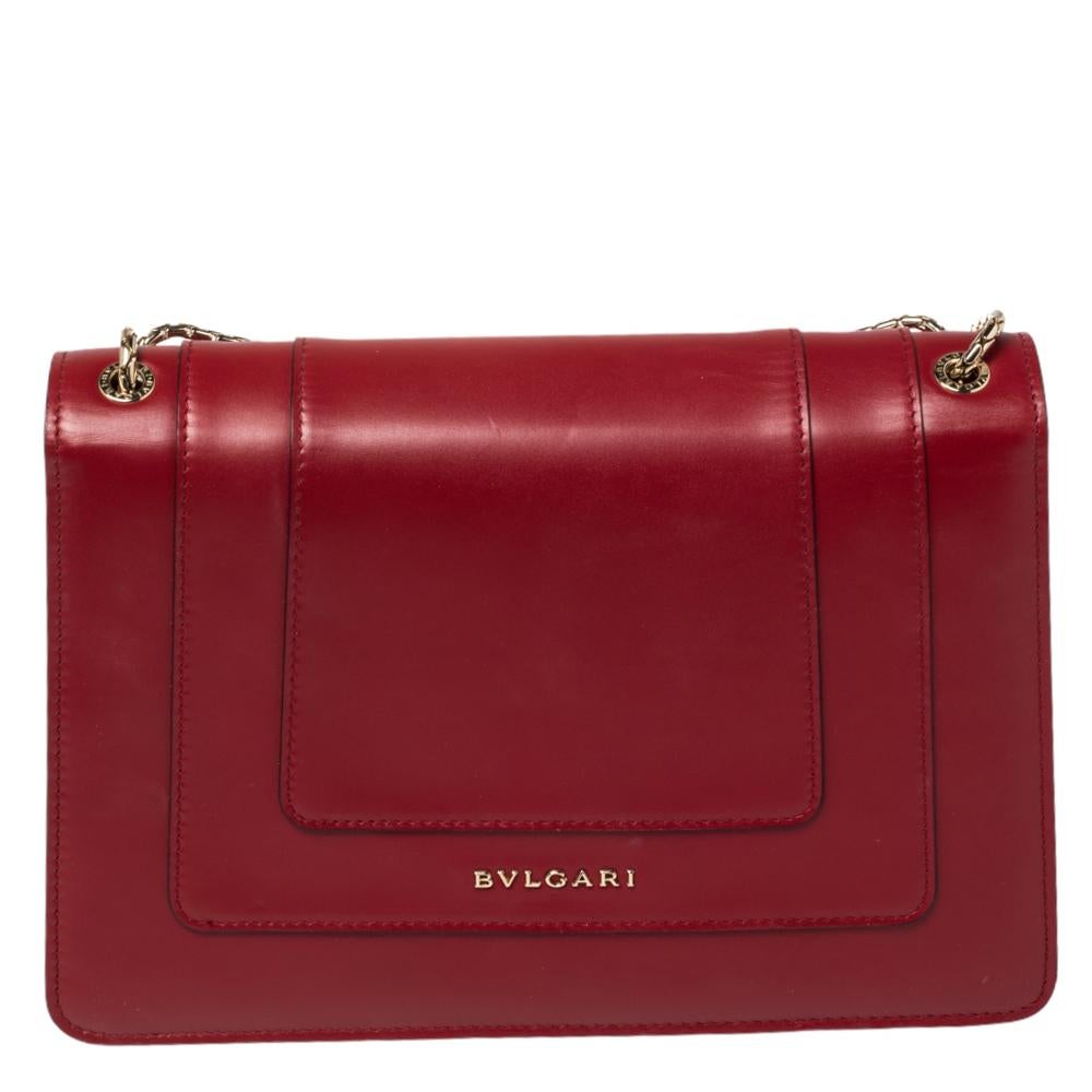 Dazzle the eyes that fall on you when you swing this stunning Bvlgari creation. Crafted from leather in a breathtaking dark red hue, the shoulder bag is styled with a flap that has the iconic Serpenti head closure. The bag has a spacious fabric