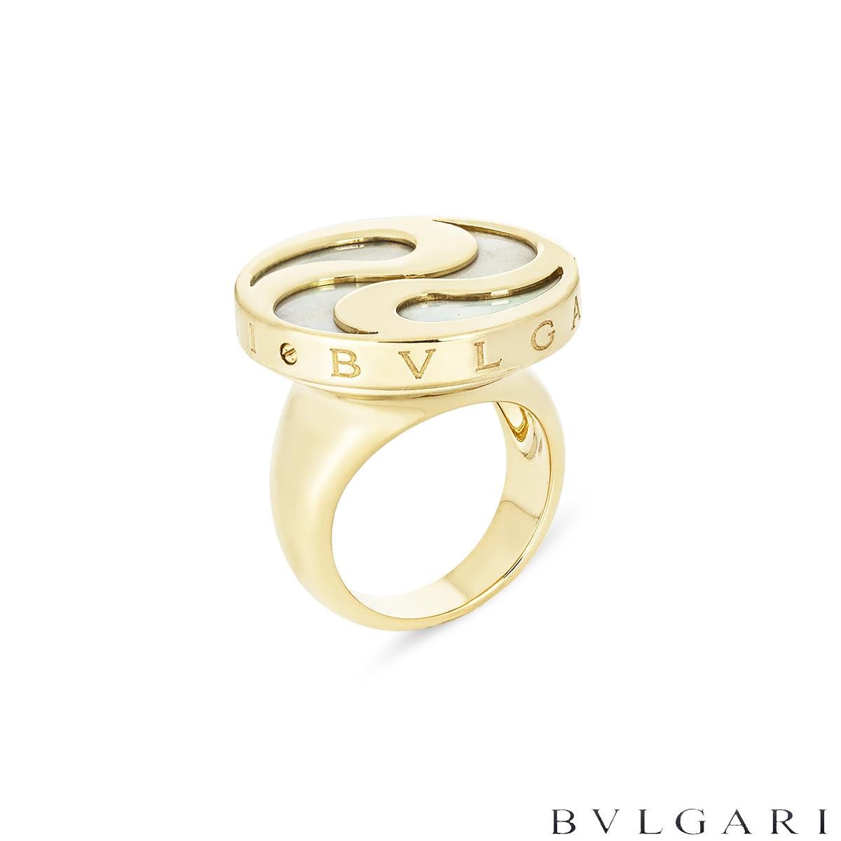 An 18k yellow gold and stainless steel ring by Bvlgari from the Optical Illusion collection. The rotating disc measures 2.4cm in width and spins in both a clockwise and anti clockwise motion. It features a mother of pearl inlay encased by a yellow