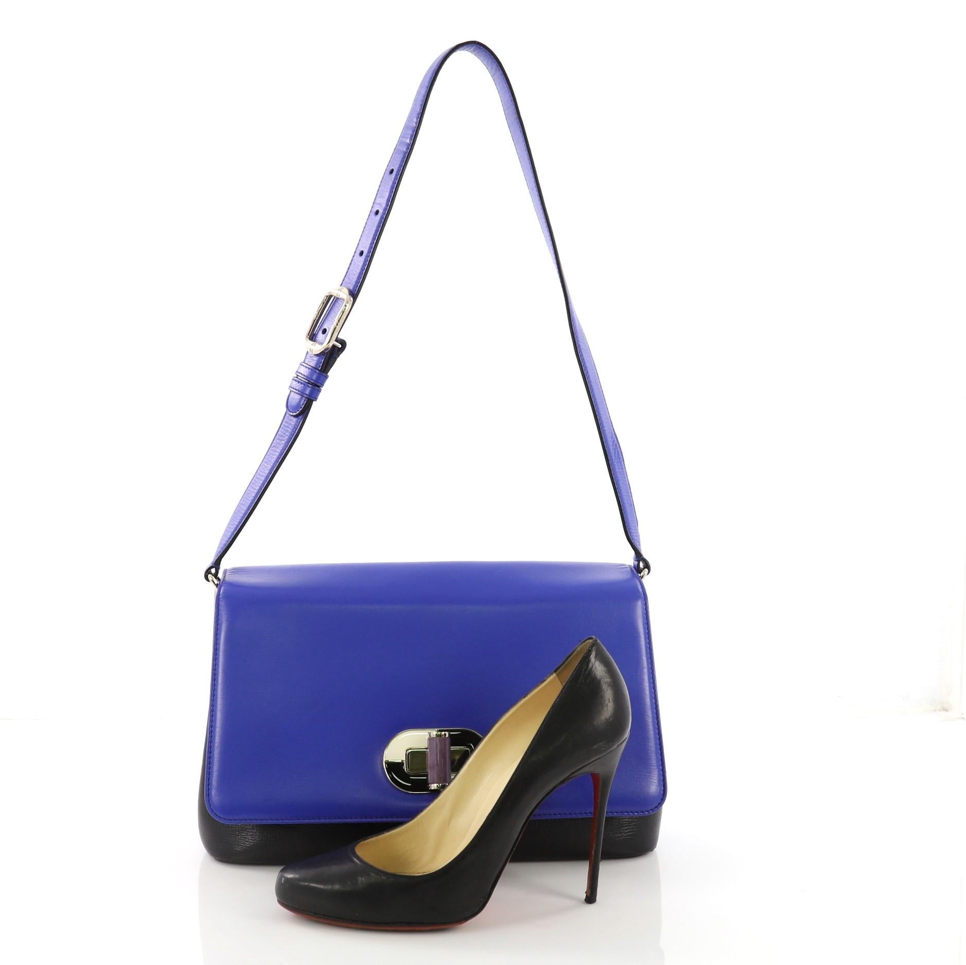This Bvlgari Icona Shoulder Bag Leather Medium, crafted from blue and black leather, features a leather shoulder strap, exterior back slip pocket, and gold-tone hardware. Its turn-lock closure opens to a blue fabric interior with two compartments
