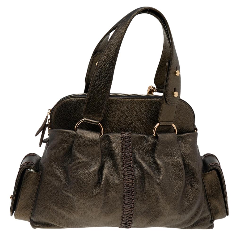 This satchel by Bvlgari exhibits fine craftsmanship and a grand appeal. It features a beautiful exterior in metallic dark brown leather with an emblem of two lions at the front. The bag opens to reveal a lined interior that can easily hold your