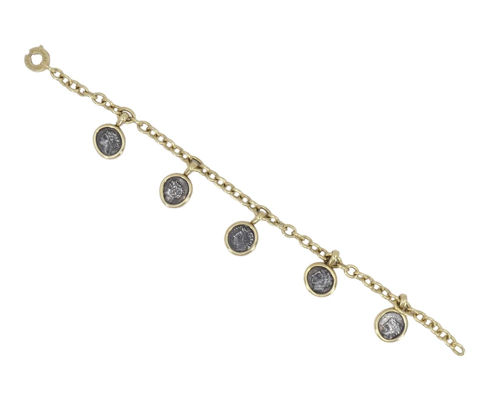 This Bvlgari Monete Ancient Coin Charm Bracelet is a captivating blend of history and elegance. Crafted from 18k yellow gold, it features five ancient coin charms that dangle gracefully from the bracelet, each telling a story of antiquity. Weighing
